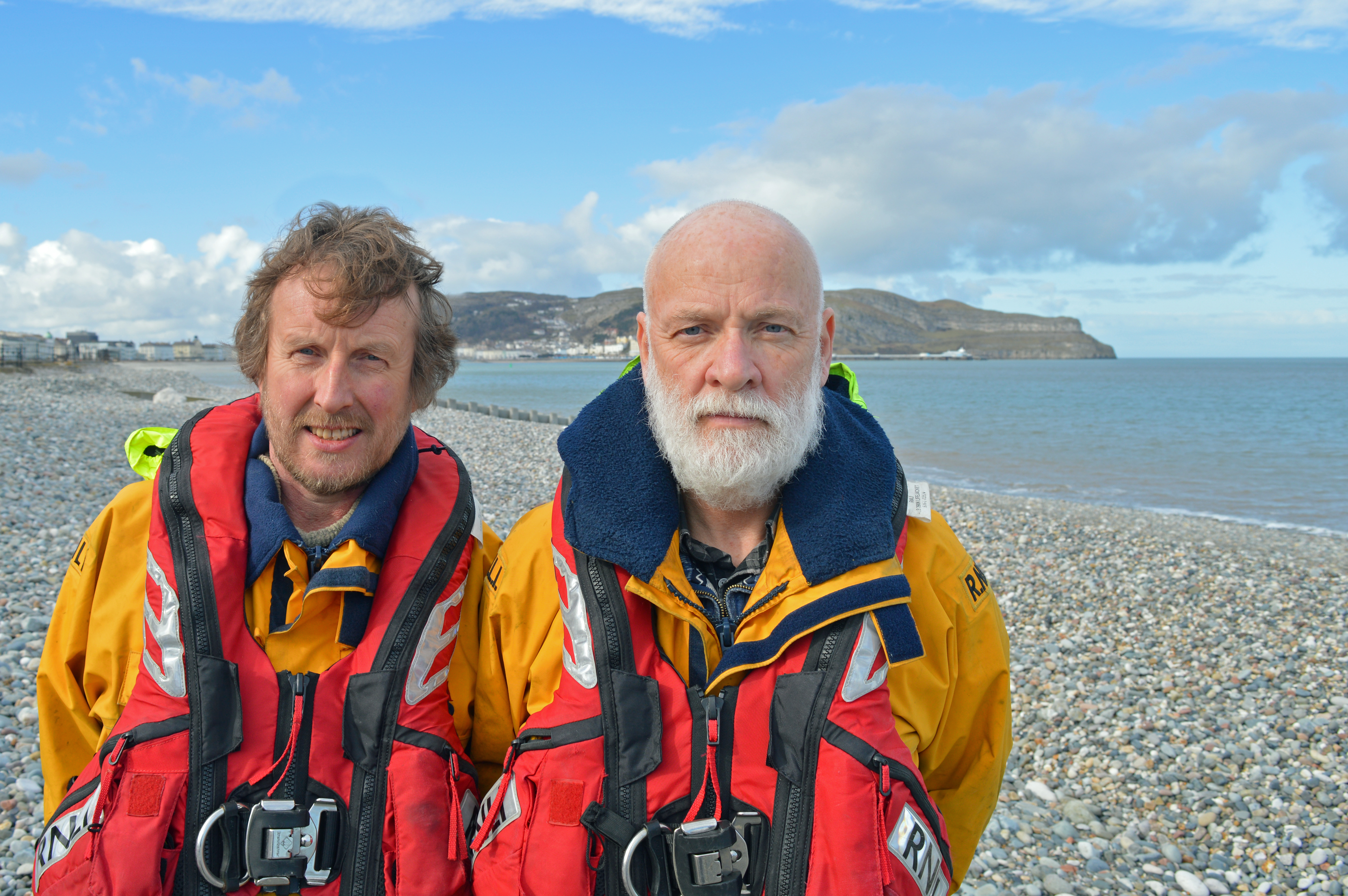 Coxswain Graham Heritage (L) and Station Mechanic Les Jones (R) pictured outside the lifeboat station - in the background the Great Orme, a welcome first sight of home for many a returning lifeboat crew.