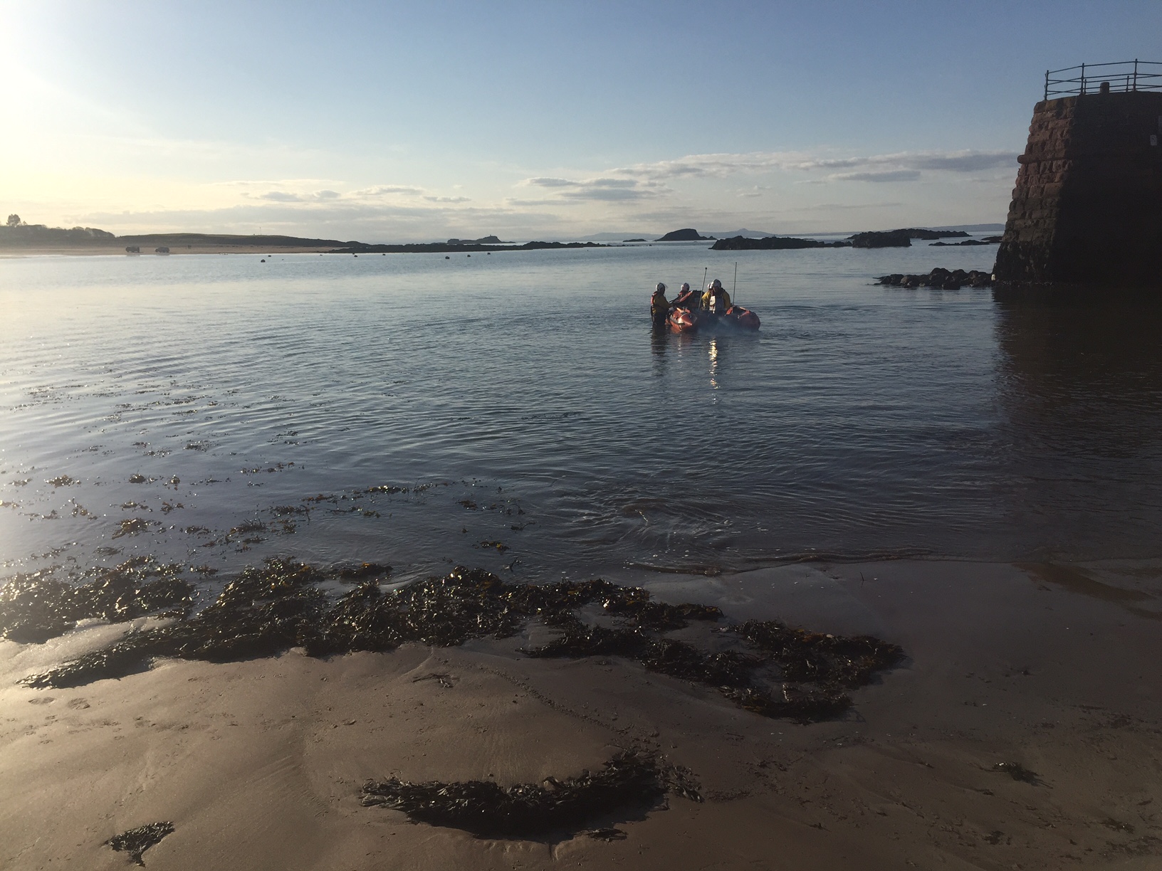 Lifeboat in water with one crew in boat starting engine whilst three crew hold boat