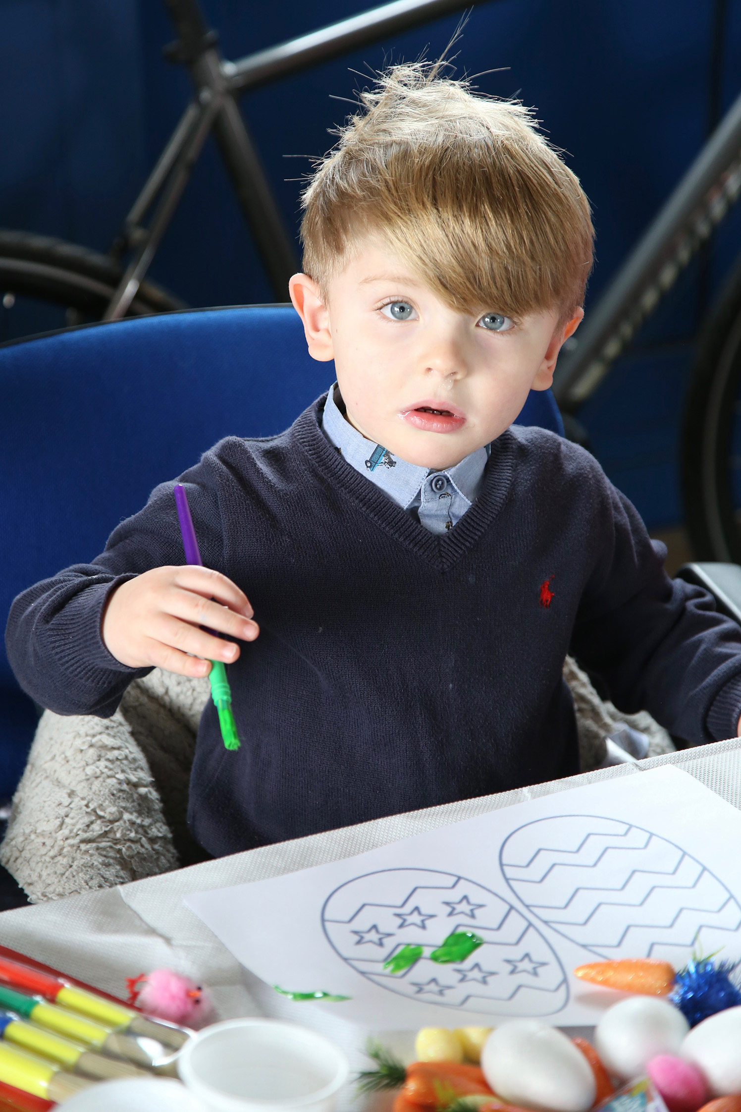 A young boy pauses with brush in hand at the art table
