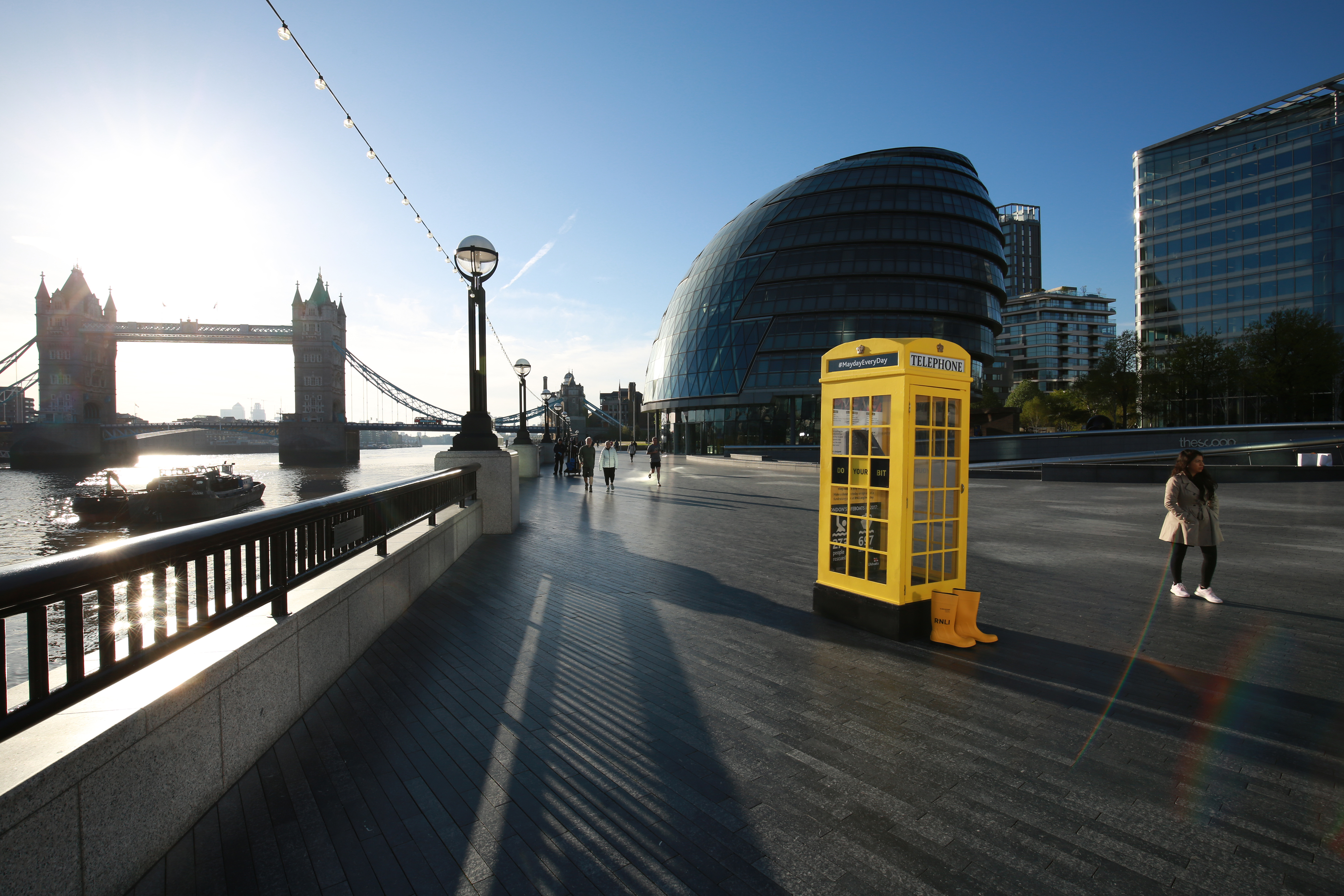 RNLI yellow phone box with City Hall and Tower Bridge in the background