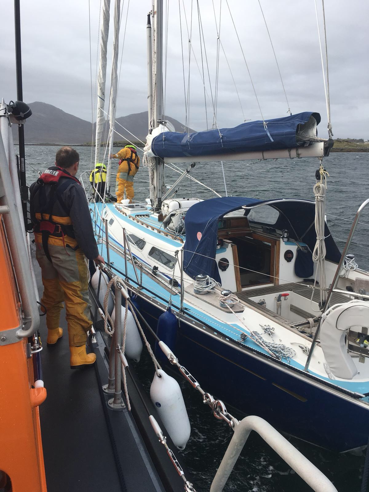 Leverburgh RNLI prepare to take the 12m yacht under tow. Both boats side by side at sea.