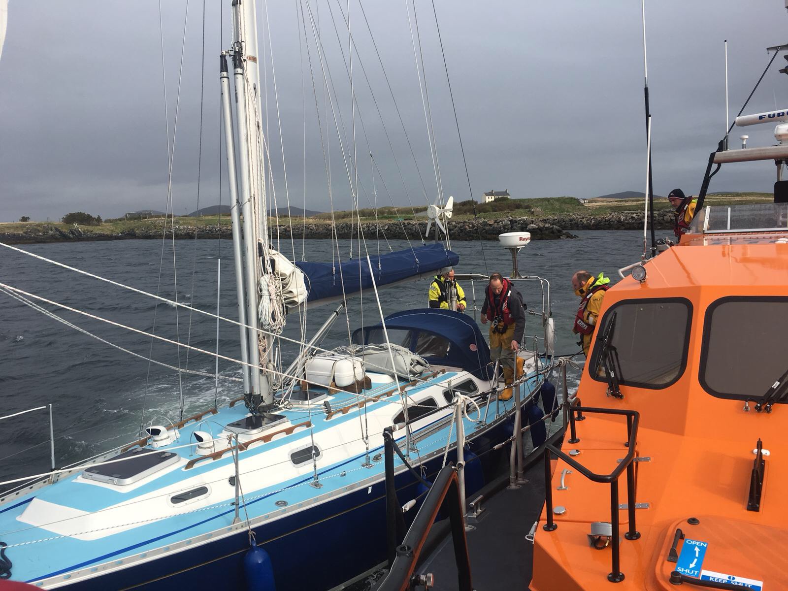 Leverburgh RNLI prepare to take the 12m yacht under tow. Both boats side by side at sea.