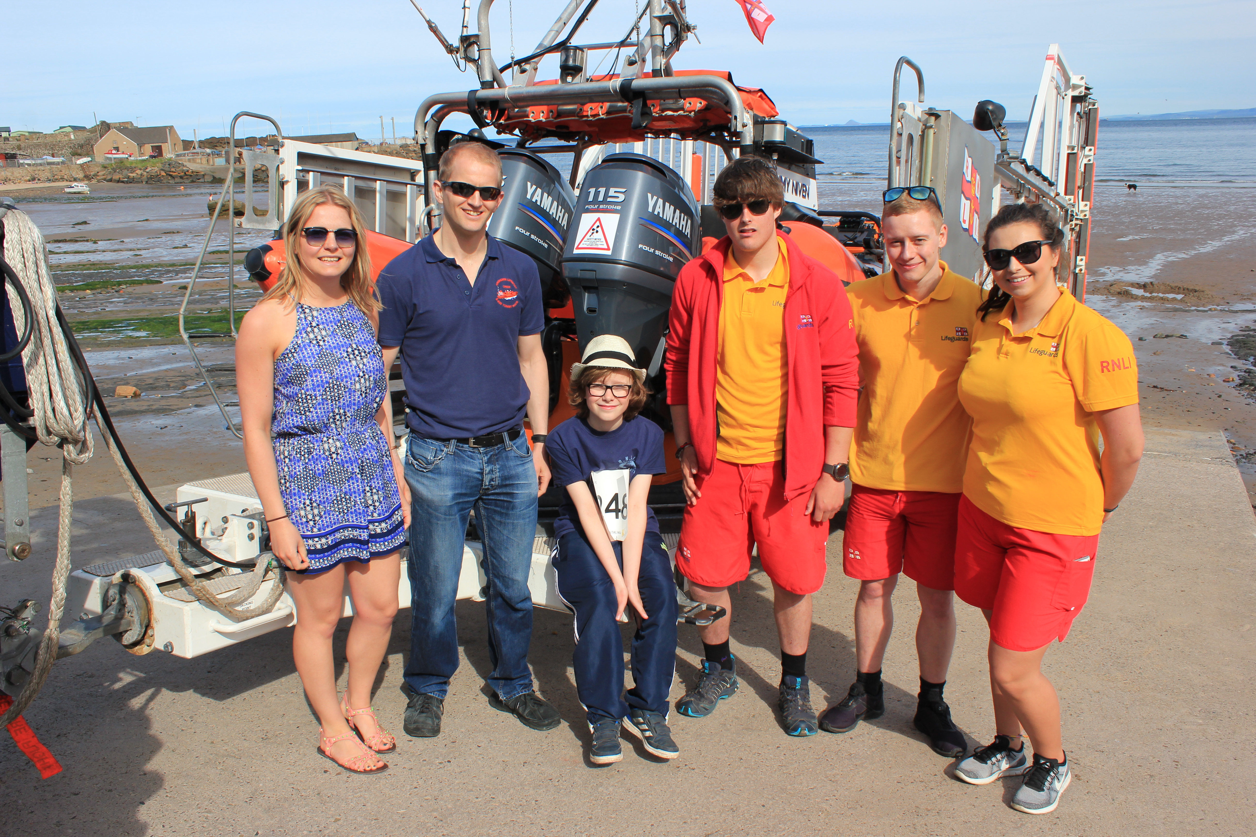 RNLI crew and lifeguards pose with young supporter who completed the full 15mile walk