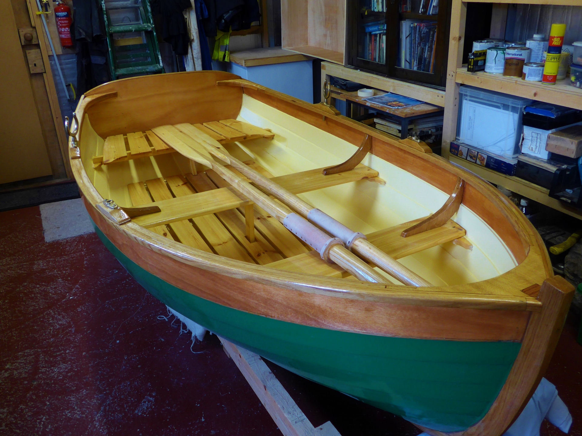 The recently finished wooden tender sits on its trailer complete with oars.