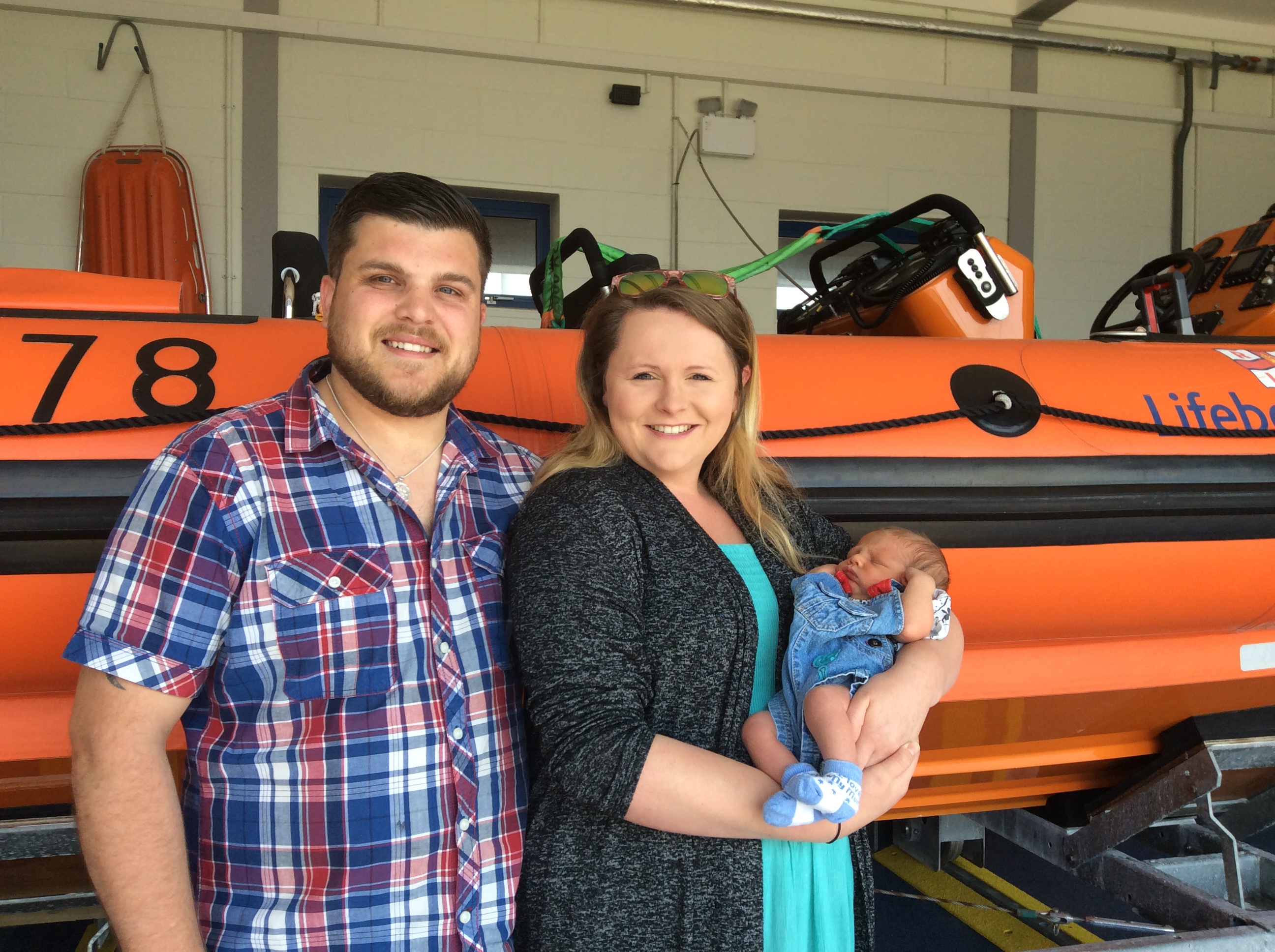 Harry, Kerry and baby Theo in front of the station's inshore lifeboat. 