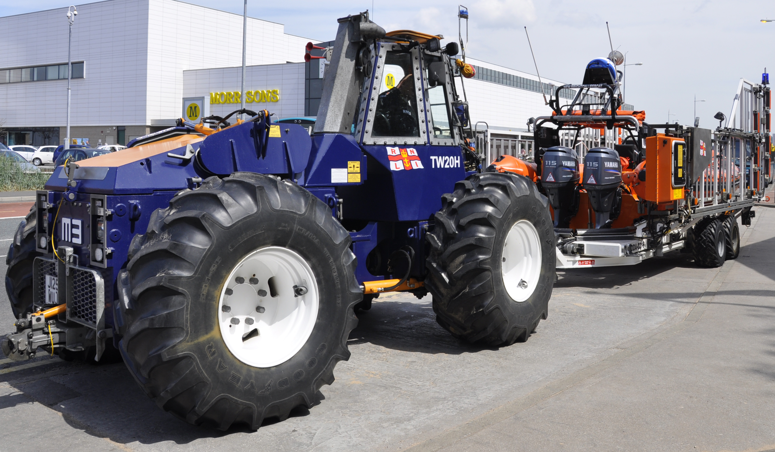 RNLI inshore lifeboat Charles Dibdin with tractor and on trailer outside the boathouse prepared for service