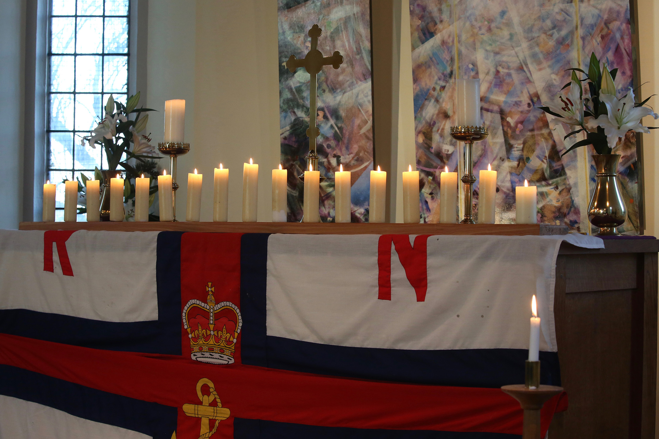 Seventeen lighted candles on the altar of Rye Harbour church which is draped in the RNLI flag