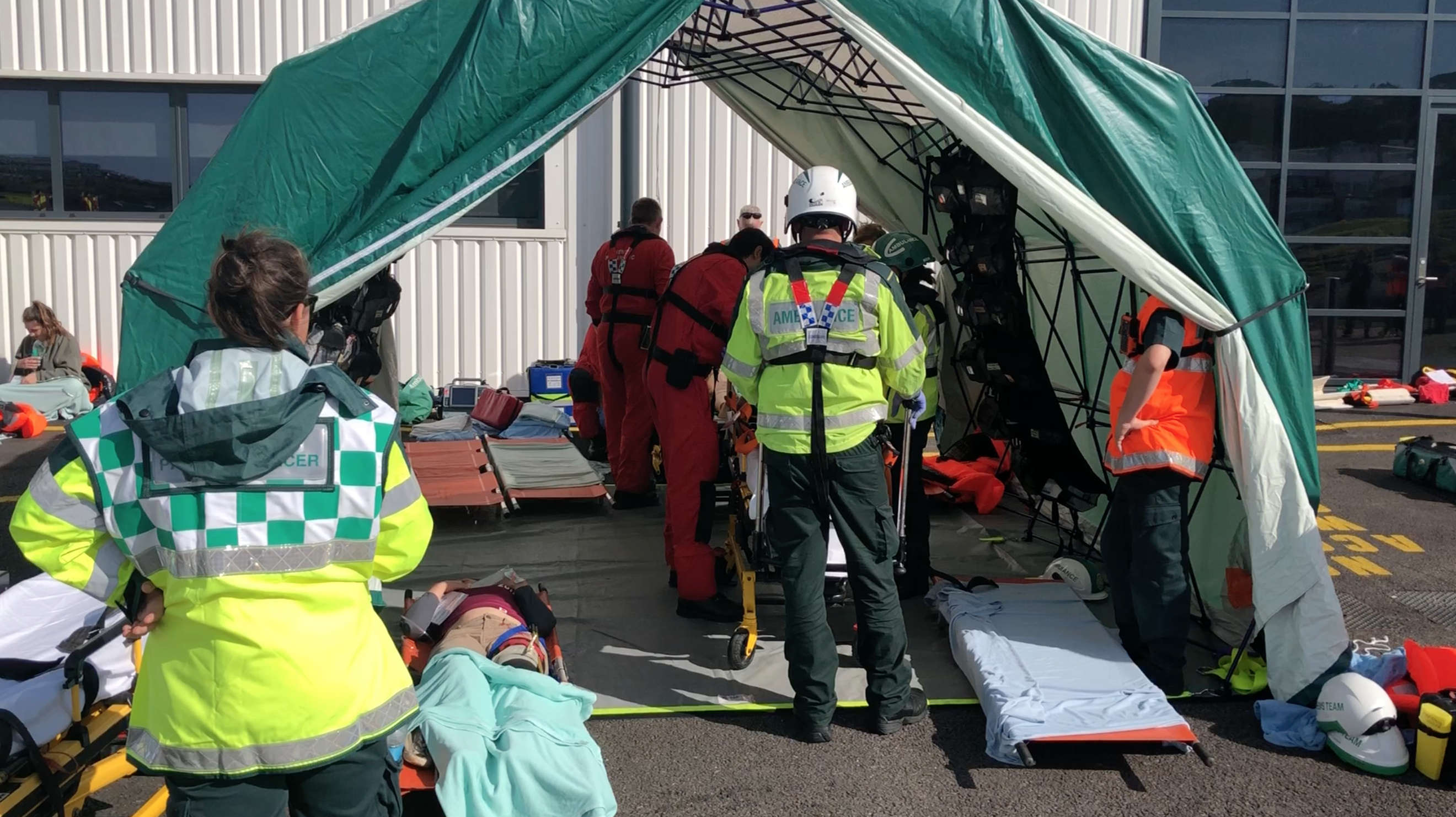 Photo of people acting as casualties being treated in an emergency hospital tent.