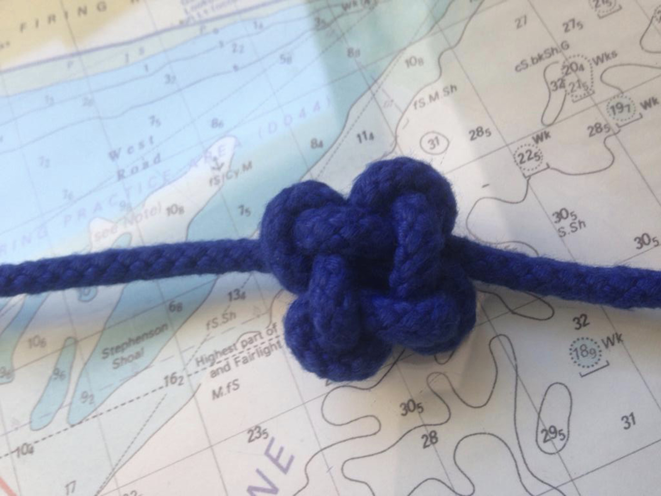 A friendship knot tied in blue cord against the background of a chart