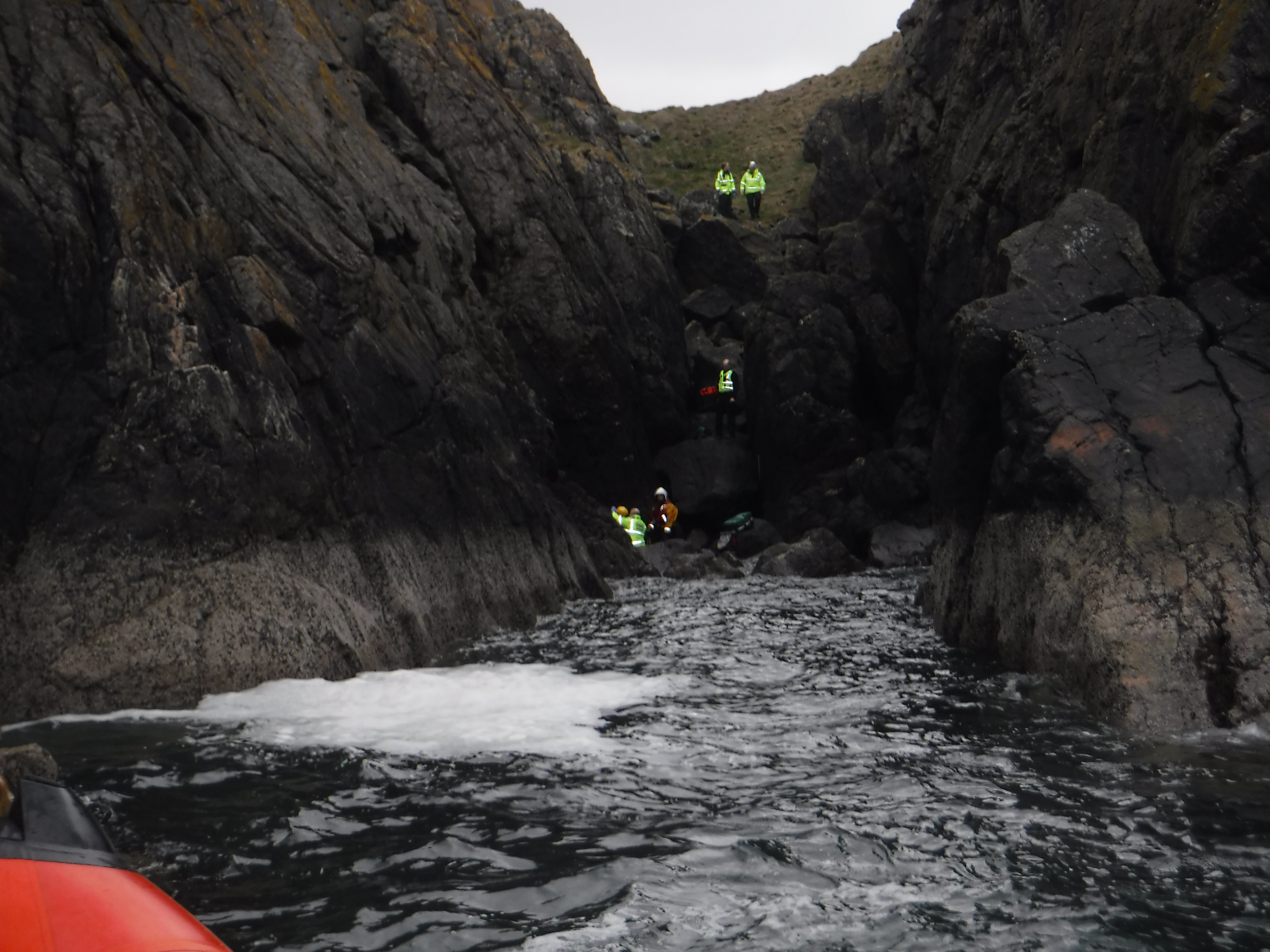 RNLI crew member at the foot of the cliffs with the casualty and member of Scottish Ambulance service