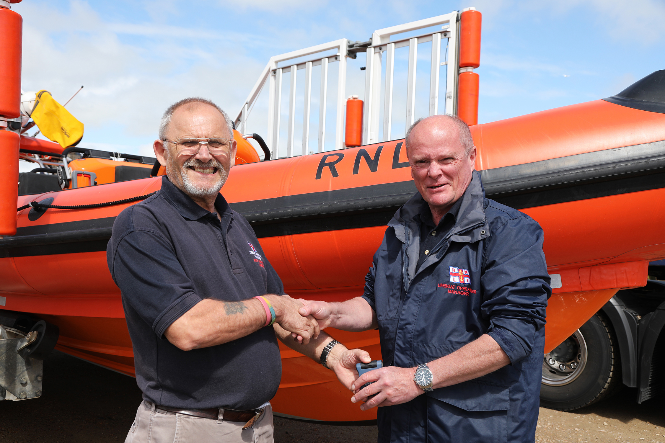 Tony Edwards, departing LOM and Mark Hall, incoming LOM, shake hands in front of the station's Atlantic 85.