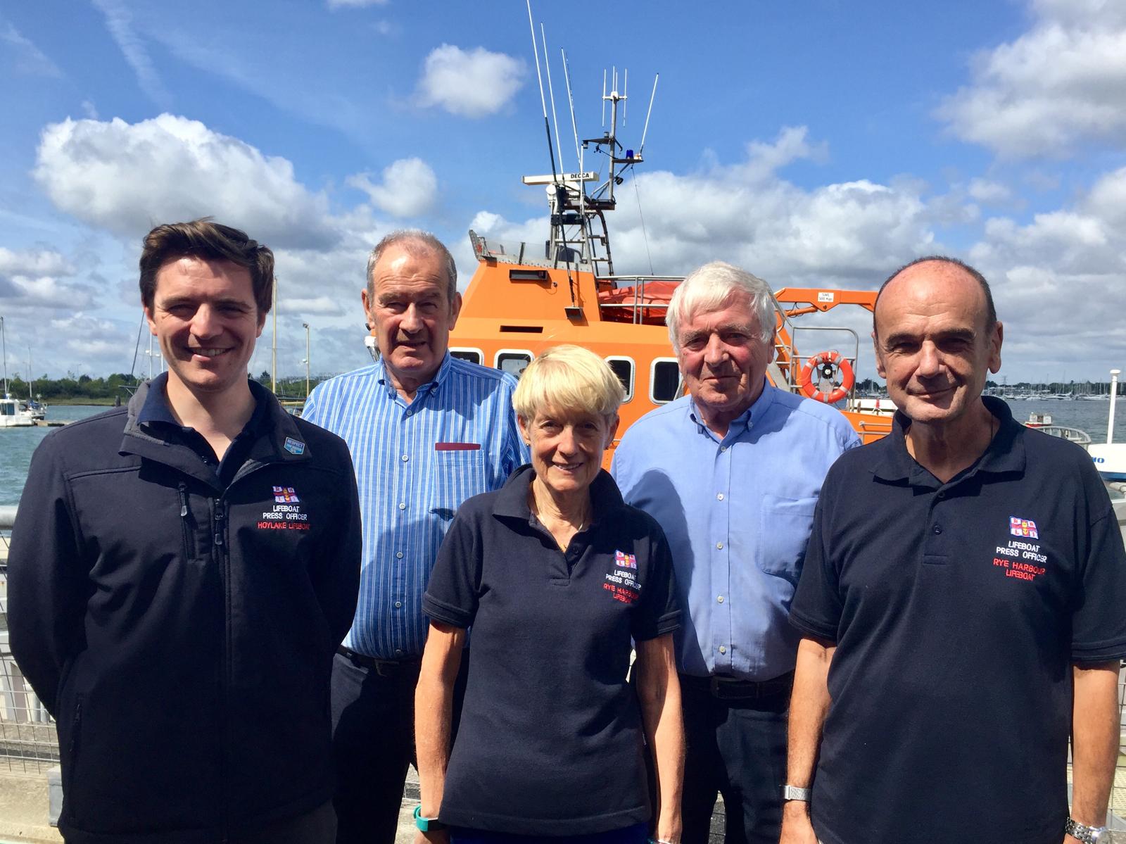 Five Press Officers on the course stand in front of an all-weather lifeboat