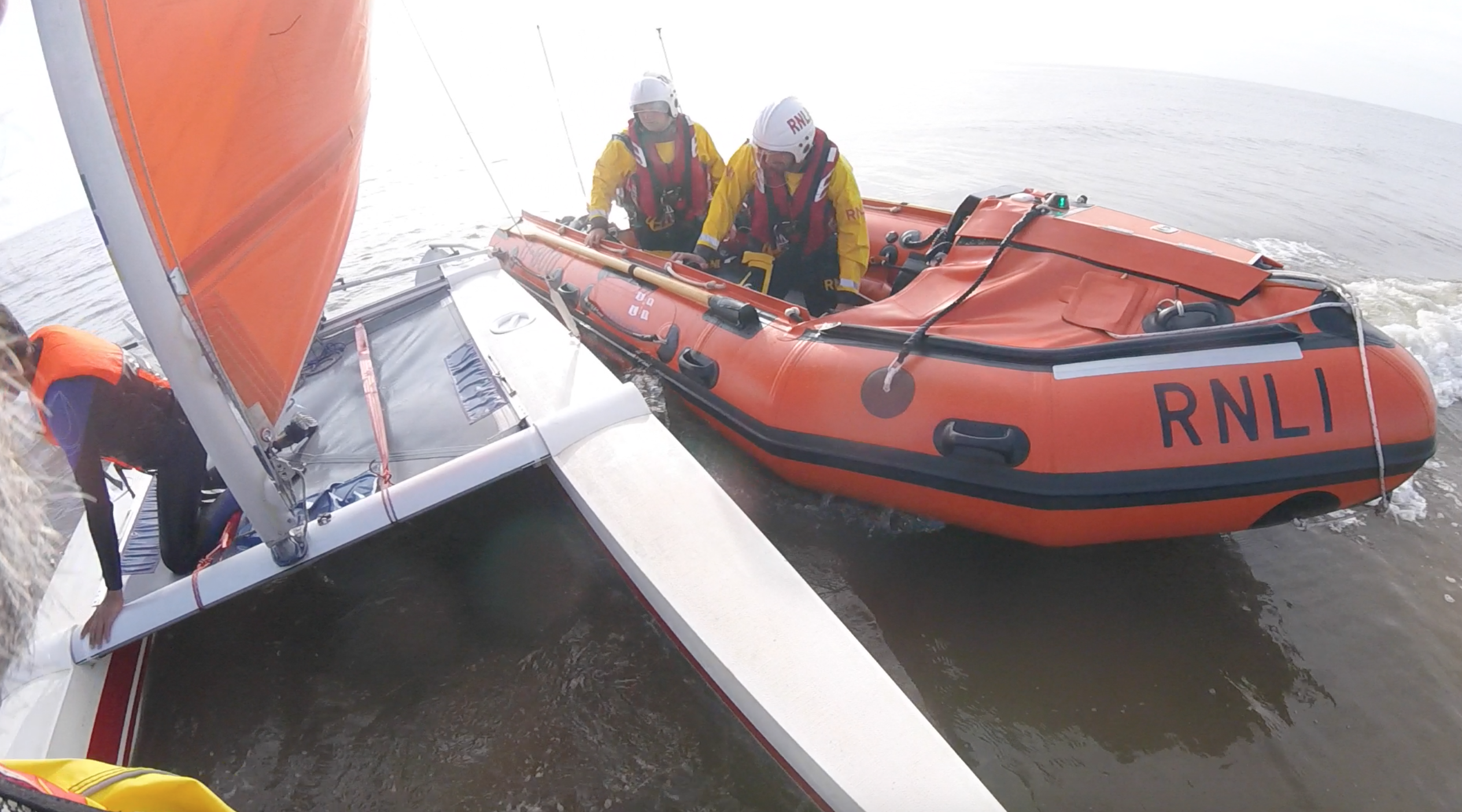 An inshore lifeboat is seen alongside a catamaran
