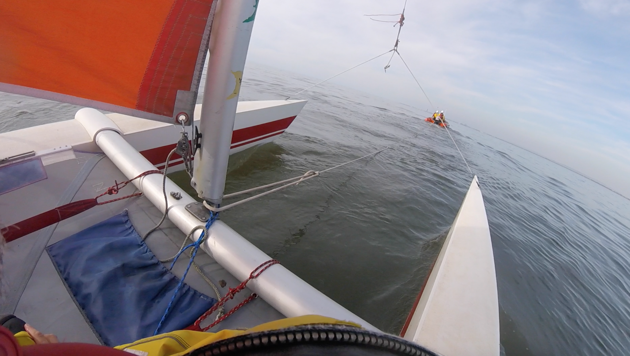 The bow of a catamaran is seen with an ILB towing ahead