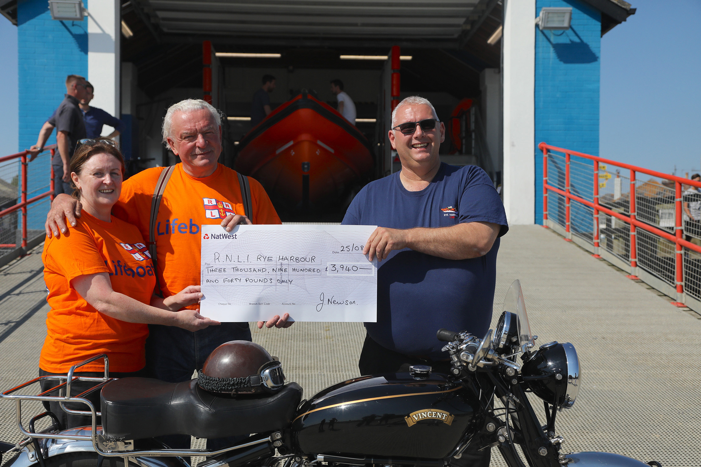 John and his fiancee presenting Paul Bolton, station LOM with the cheque in front of the boathouse
