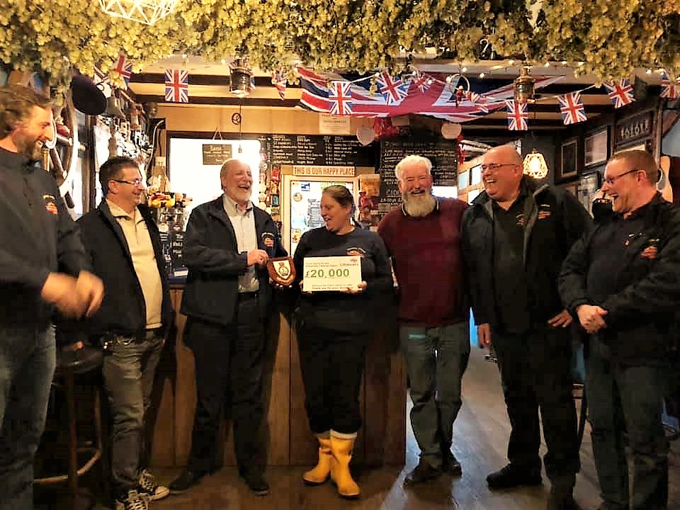 Landlady and crew member Rachel Collier with husband Chris presenting Sheerness RNLI Lifeboat coxswain Robin Castle MBE with the cheque for £20,000 watched by her crewmates and customers at the Admirals Arm
