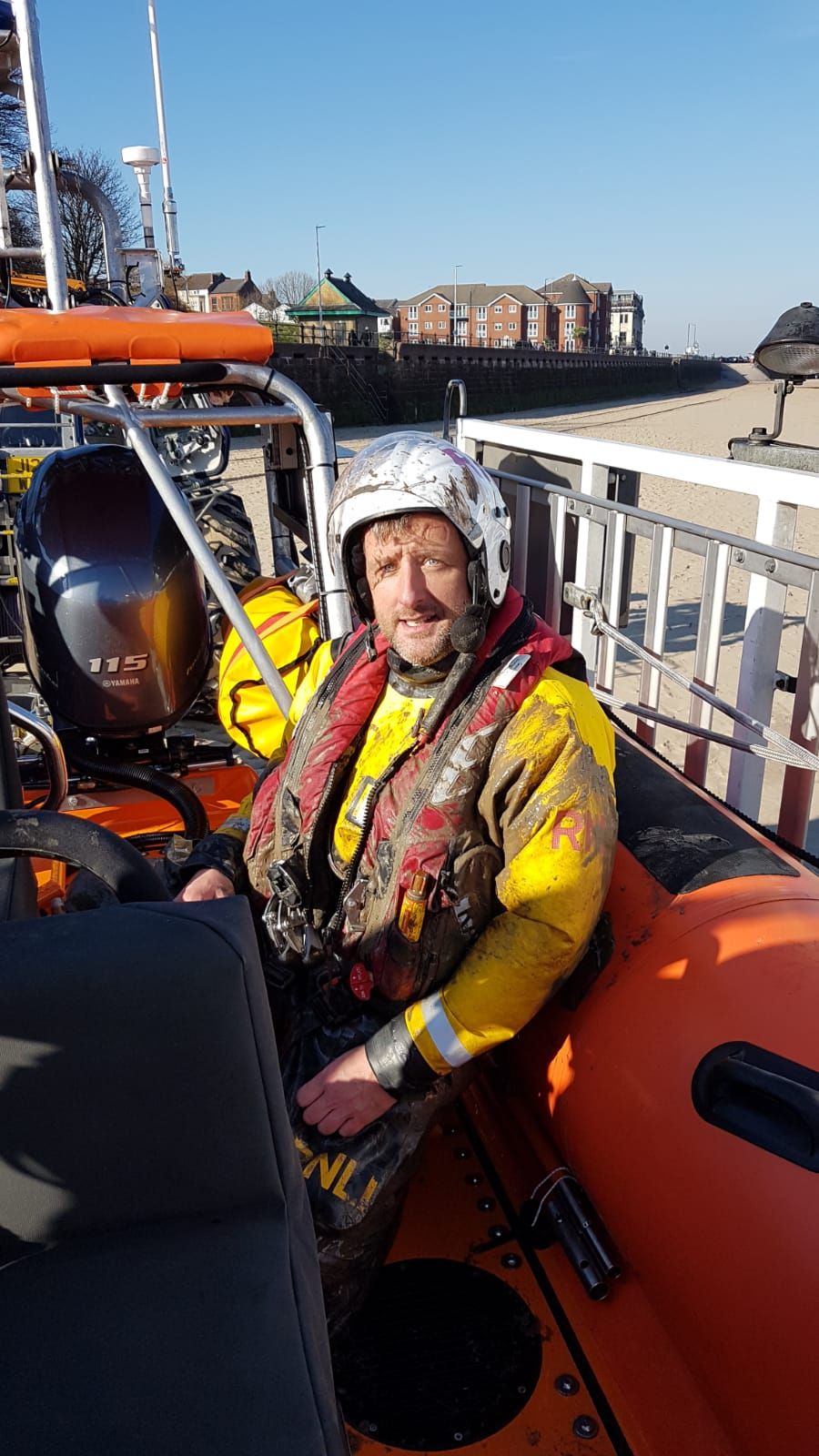 Mud-covered Trevor Boyes sitting in full PPE on the lifeboat 
