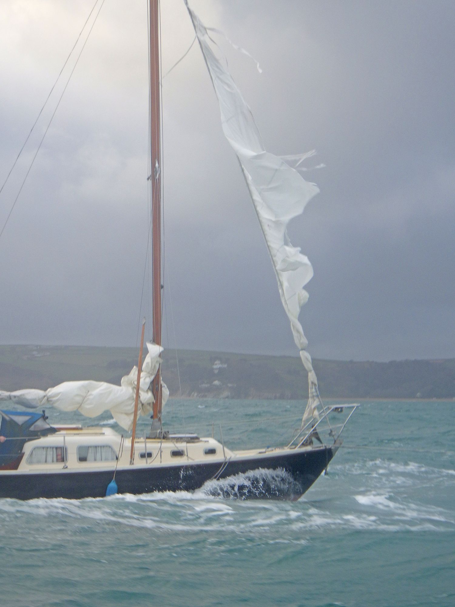Yacht with shredded sails under tow in Start Bay