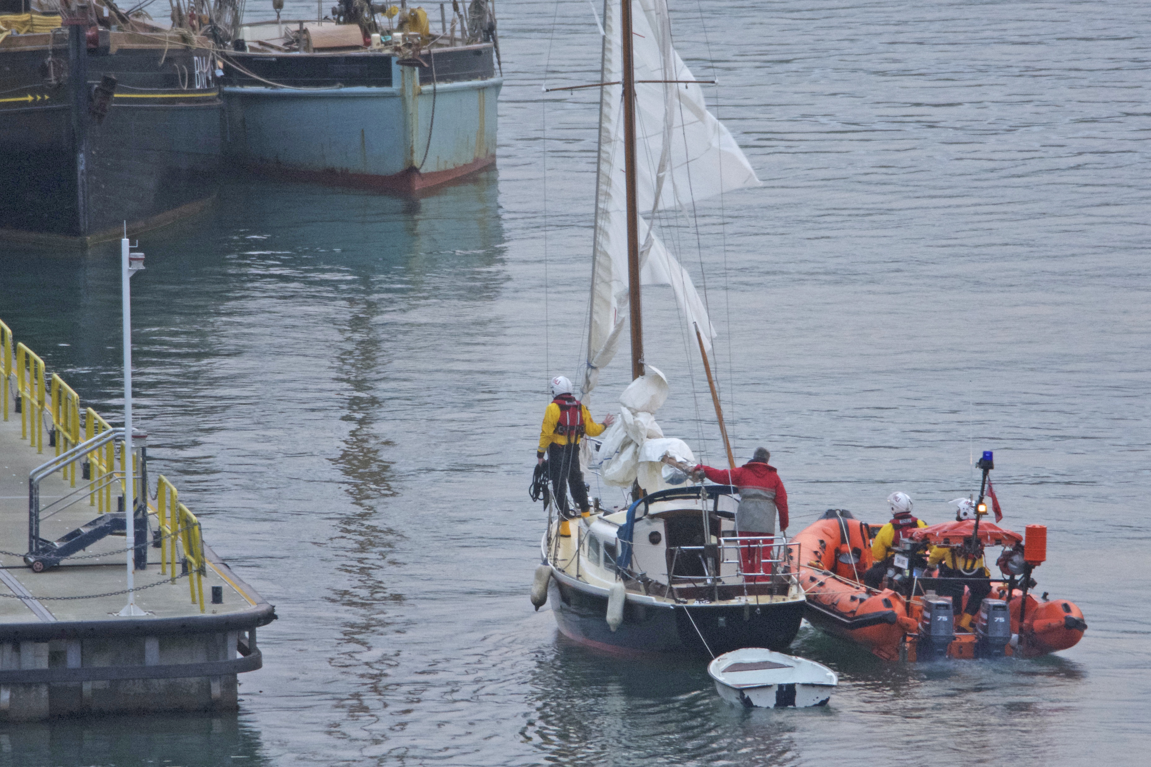 Yacht with shredded sails being berthed by RNLI Dart inshore lifeboat.