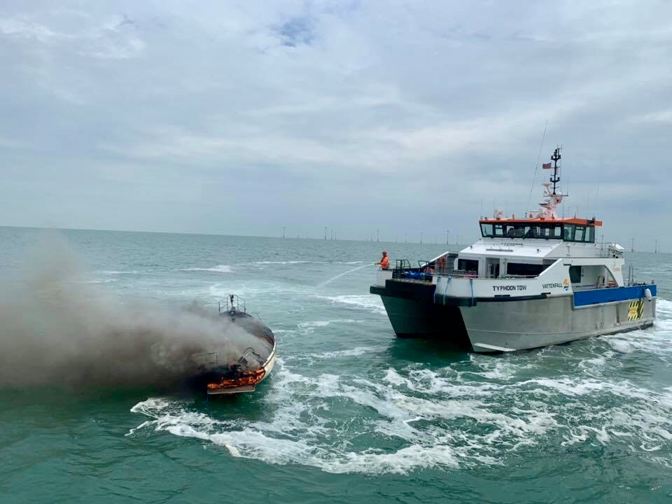 A burning yacht being hosed down by an attending Wind Farm vessel.