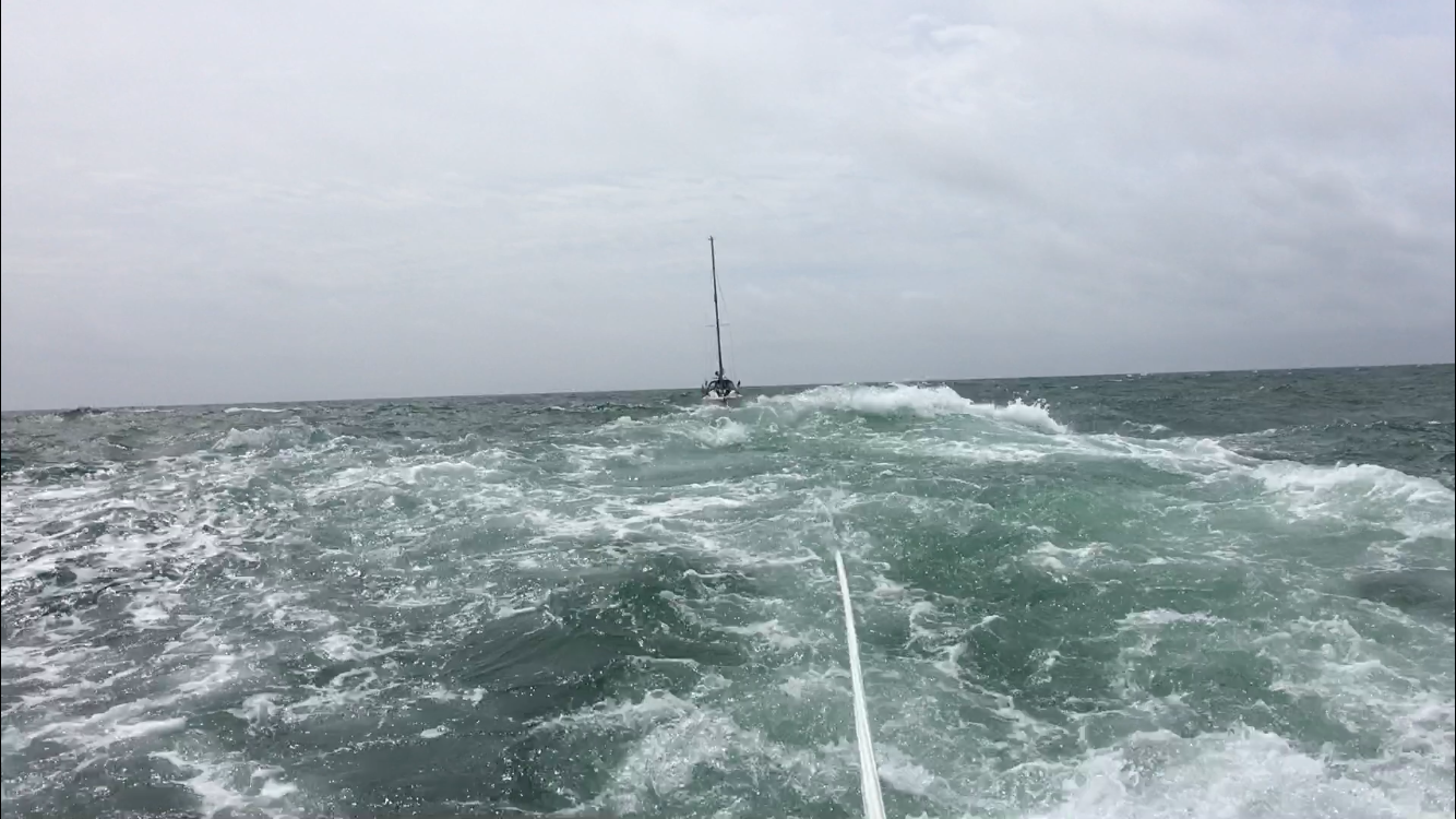 Yacht being towed by lifeboat in rough water