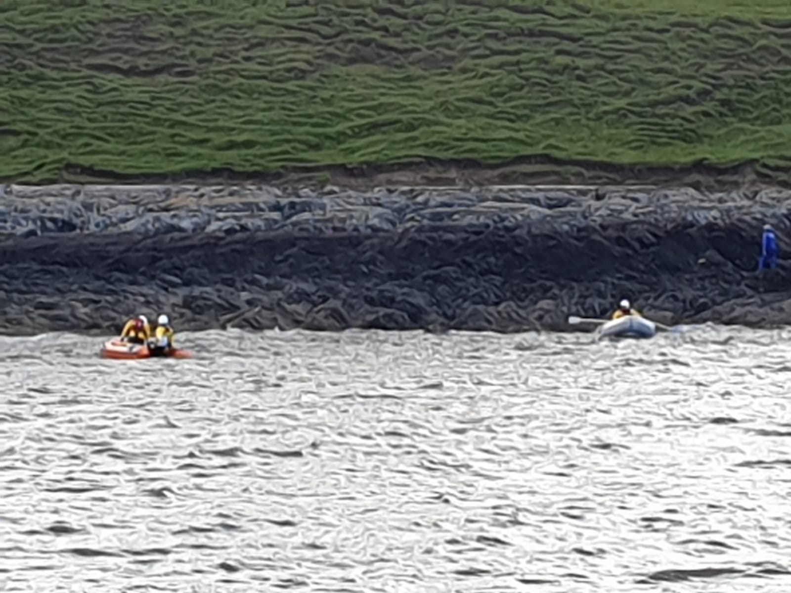 Lifeboat Crew retreiving Dinghy from rocky coastline