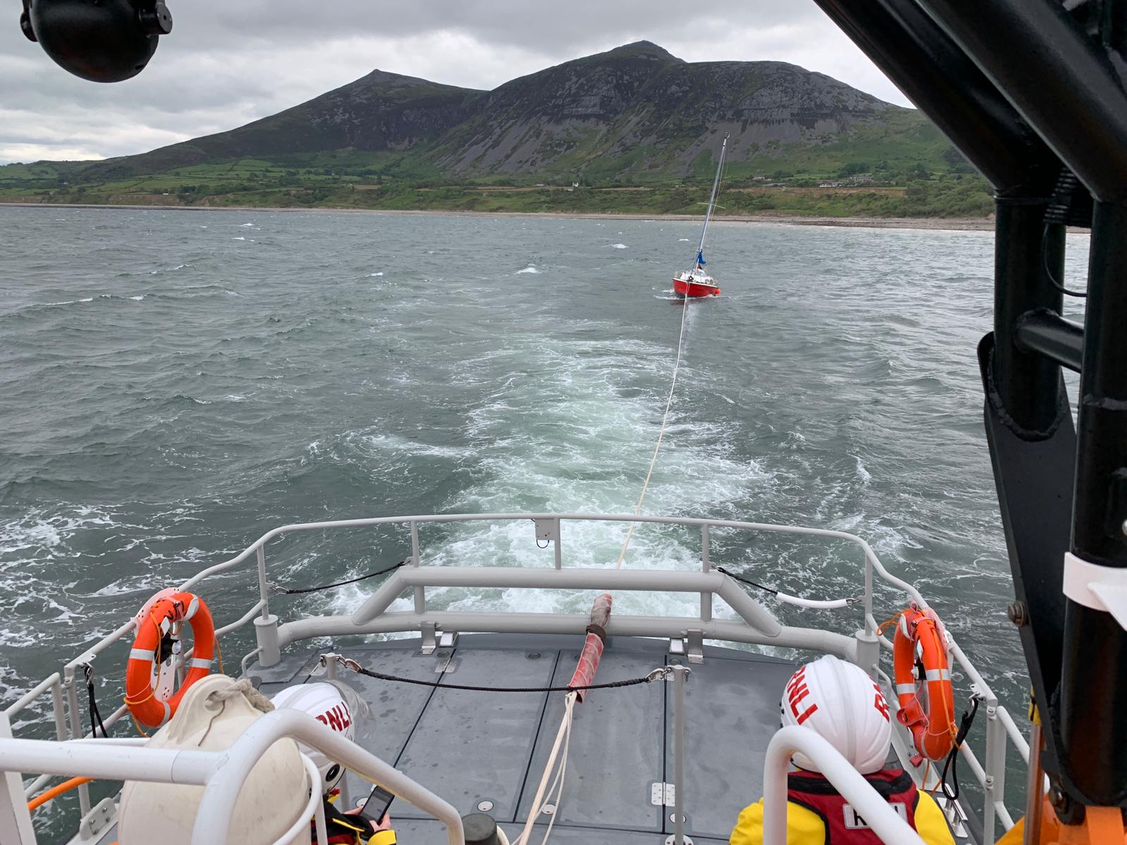 Crew members keep an eye on the yacht while under tow