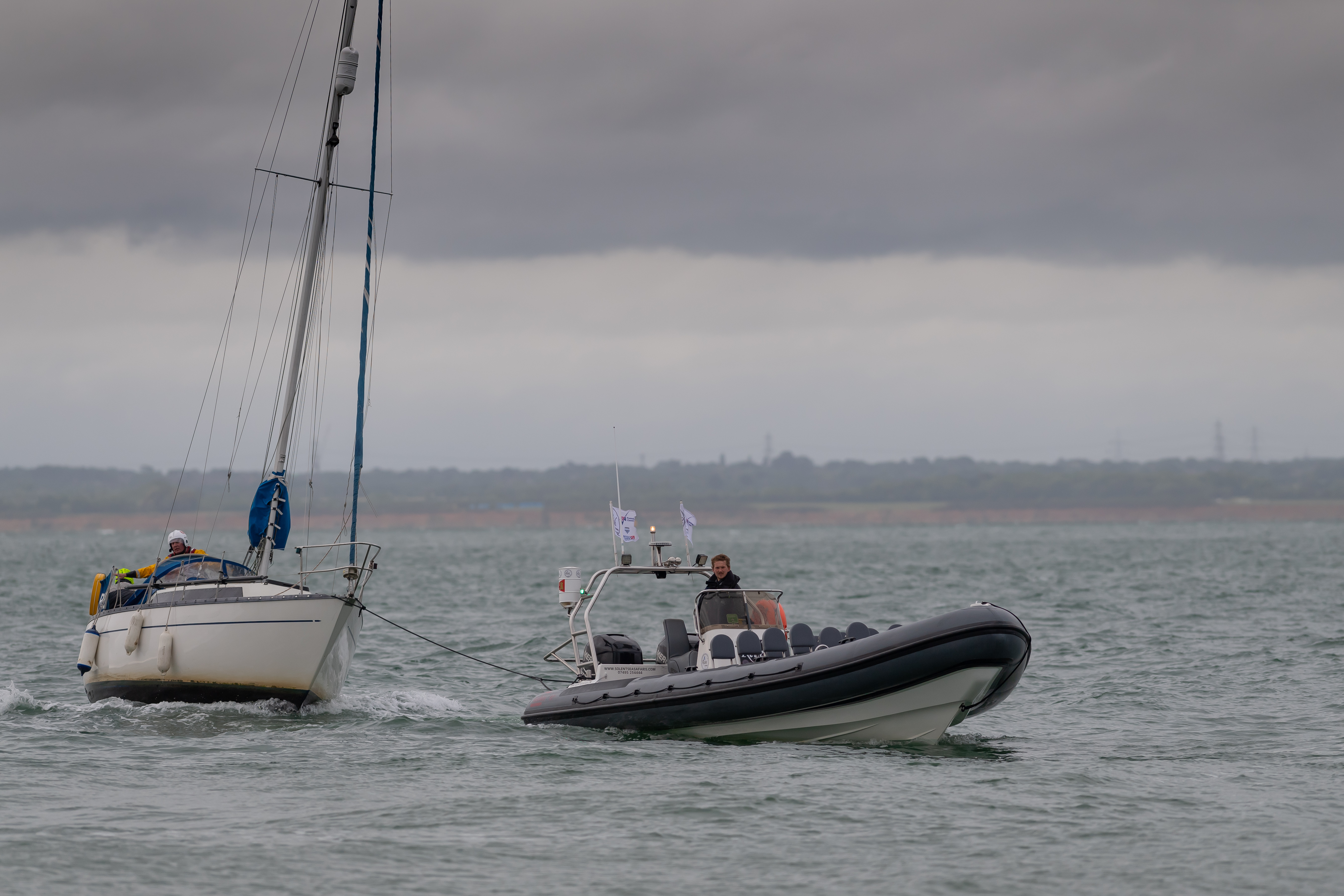 Yacht is towed towards Cowes by a RIB.