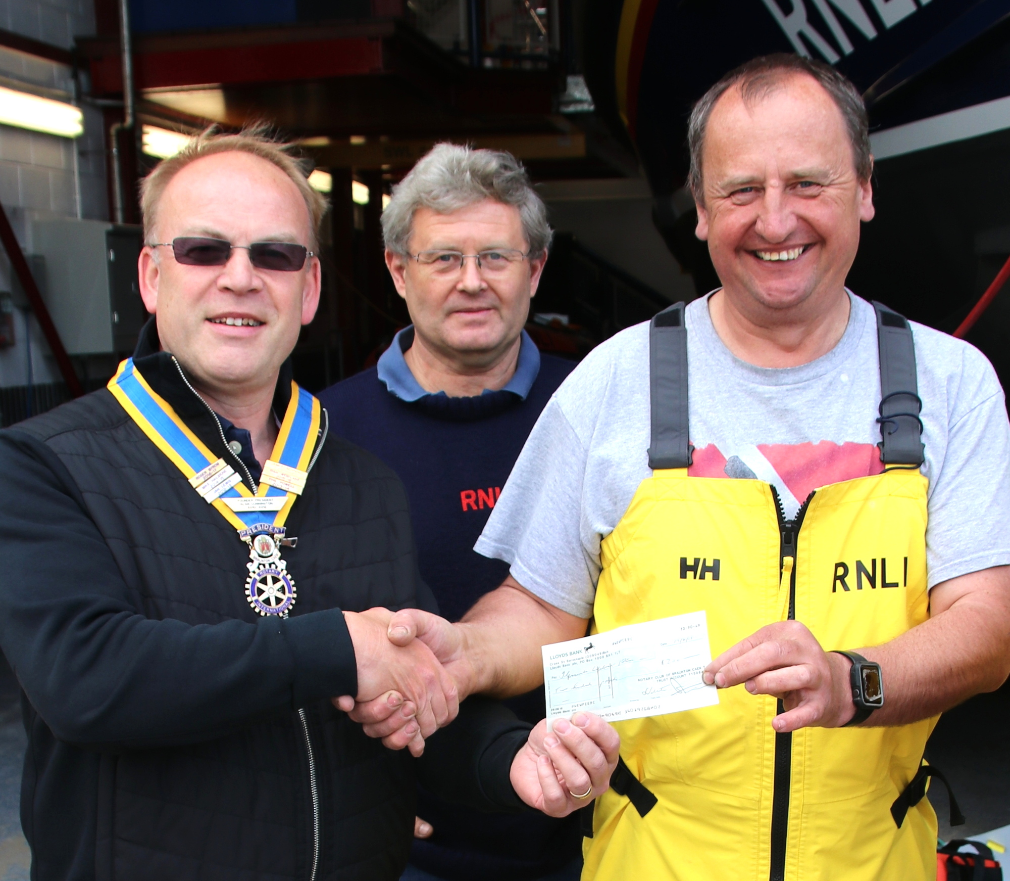 Chris Andrews of Caen Rotarians presents the cheque to Leigh Hanks of Ilfracombe RNLI outside the lifeboat station