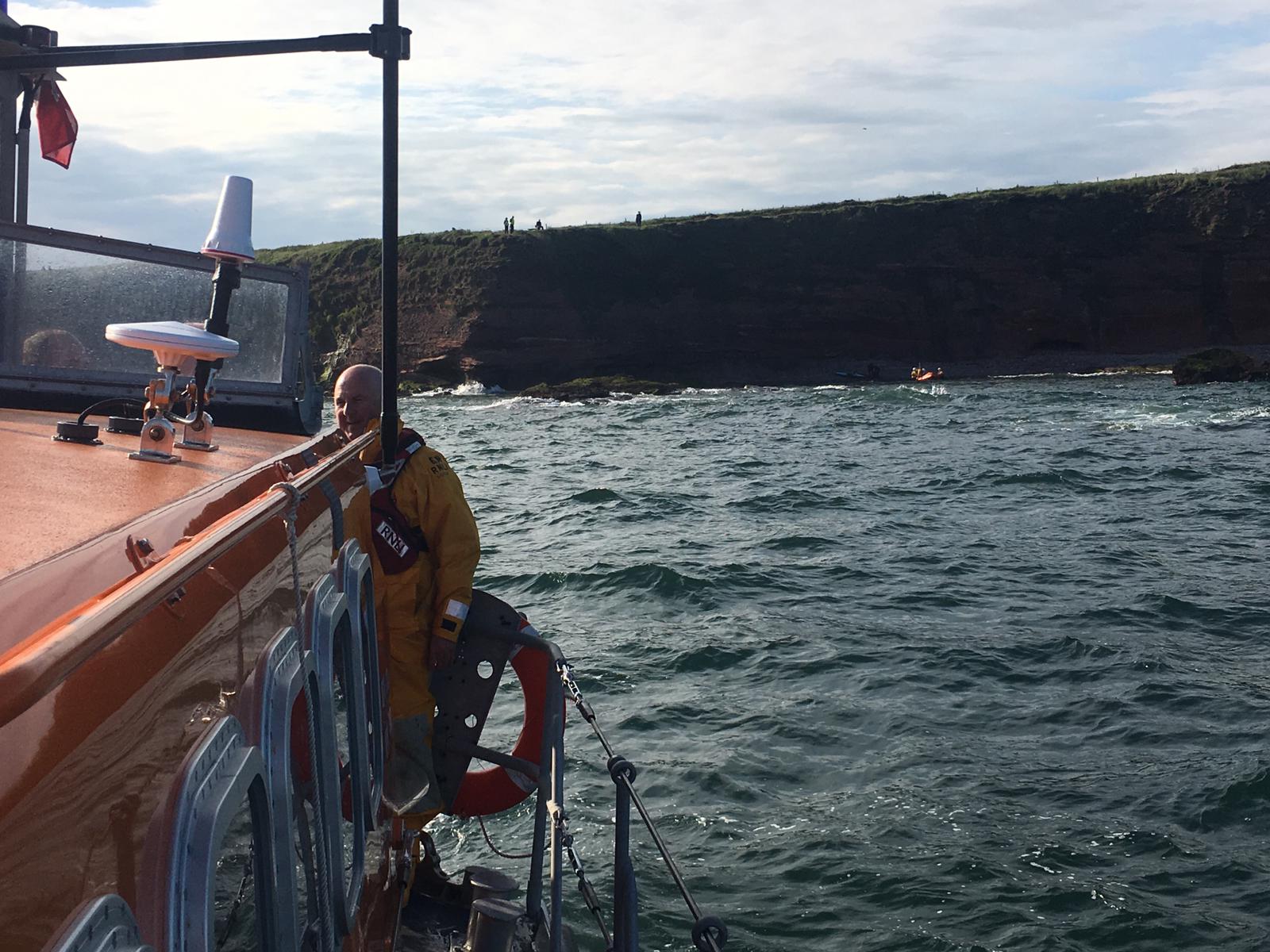 Photo of ILB &amp; kayakers on shoreline at foot of cliffs taken from ALB