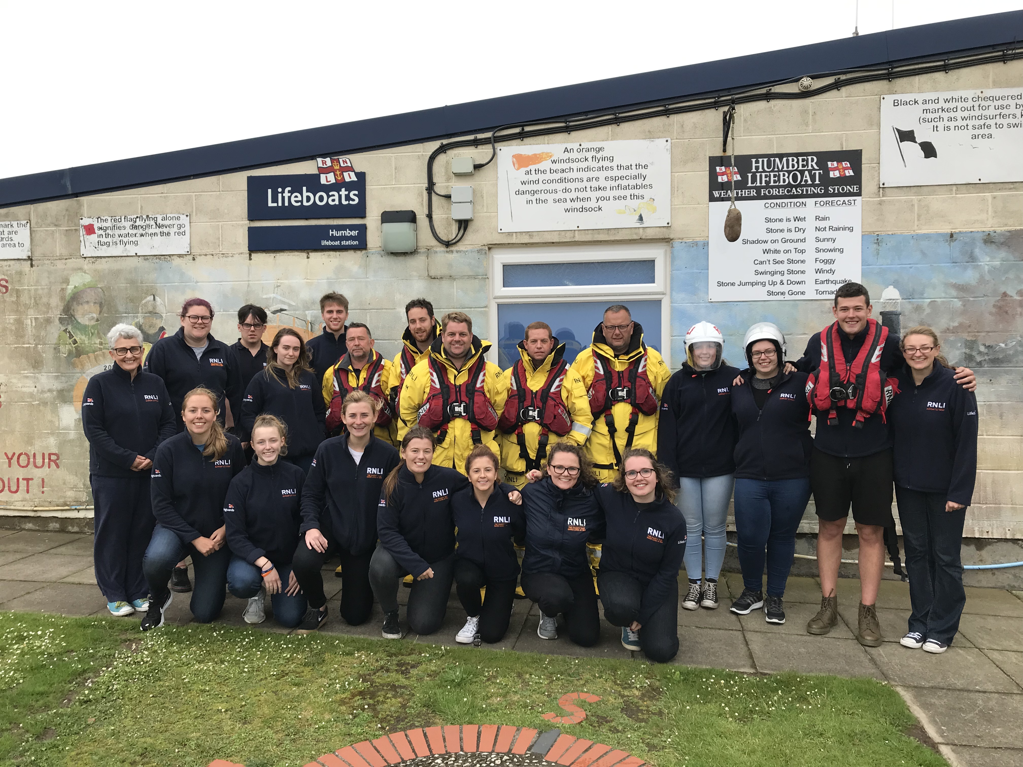 Humber Lifeboat crew and North East Face-to-Face Team stand outside Humber Lifeboat Station. 21 people in the photo. Crew are in their lifeboat gear.
