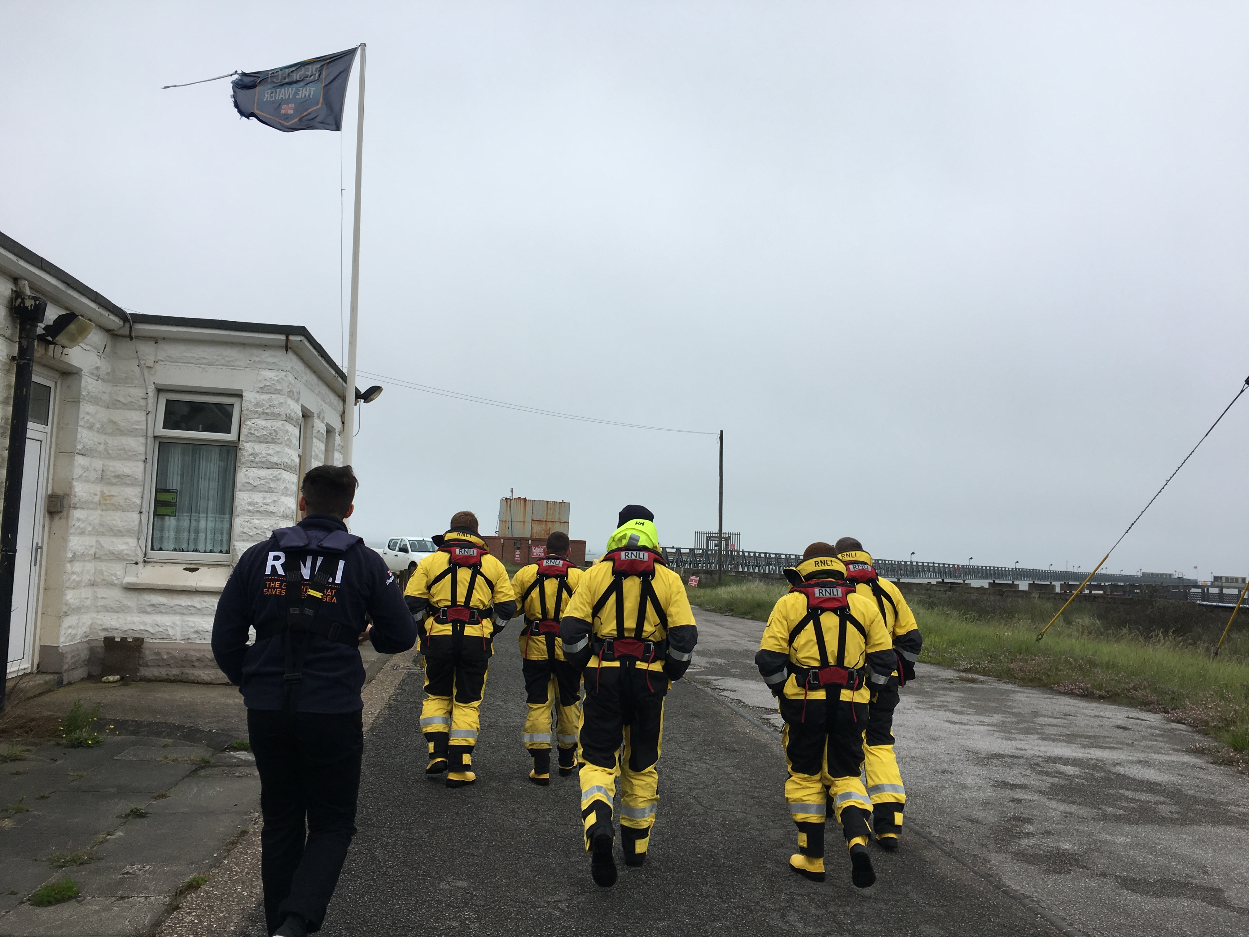 The lifeboat crew walk rowards the jetty with a member of the Face-to-Face Team