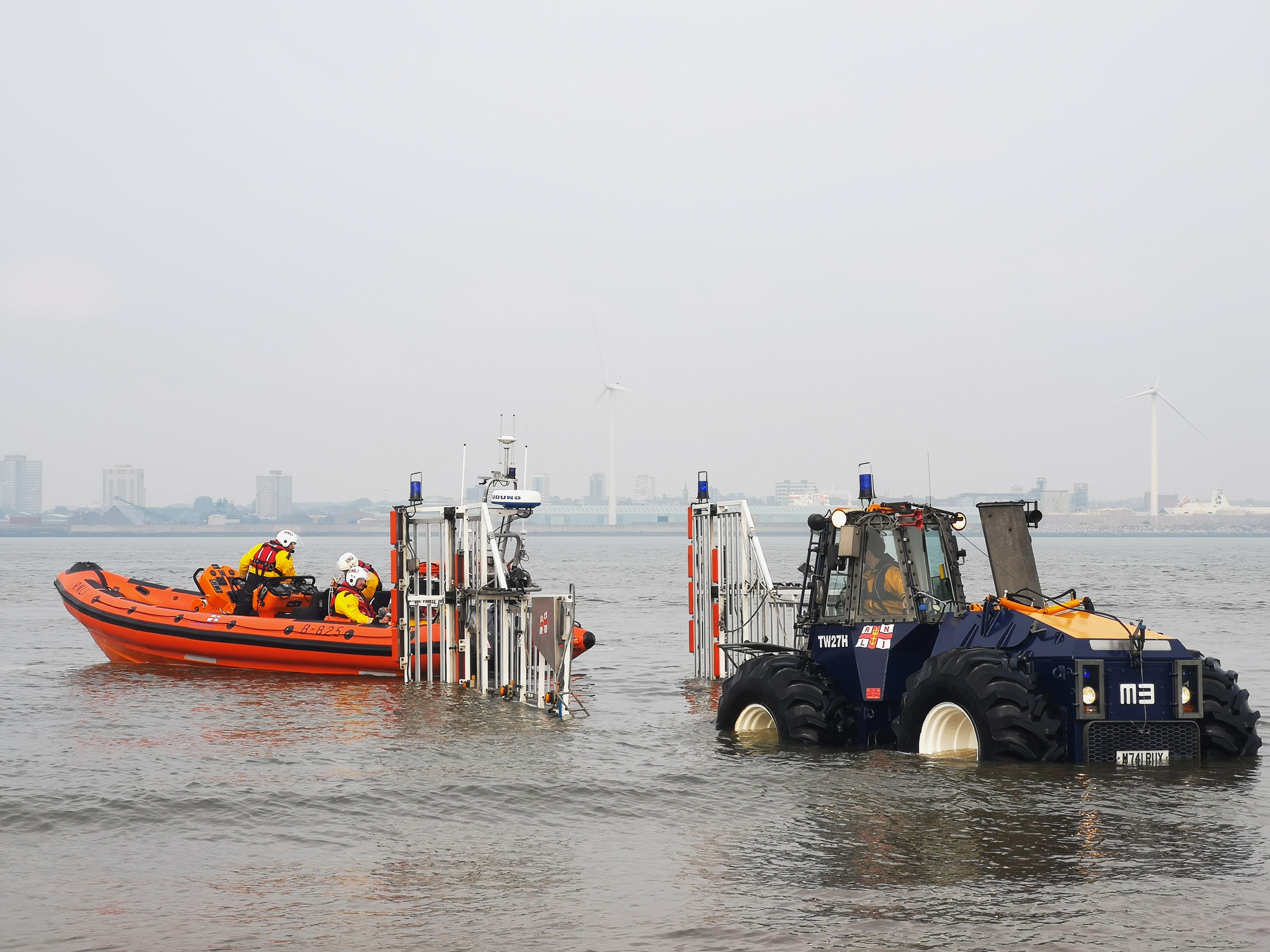 The lifeboat is reversing into the carriage with the tractor ready to tow from the water