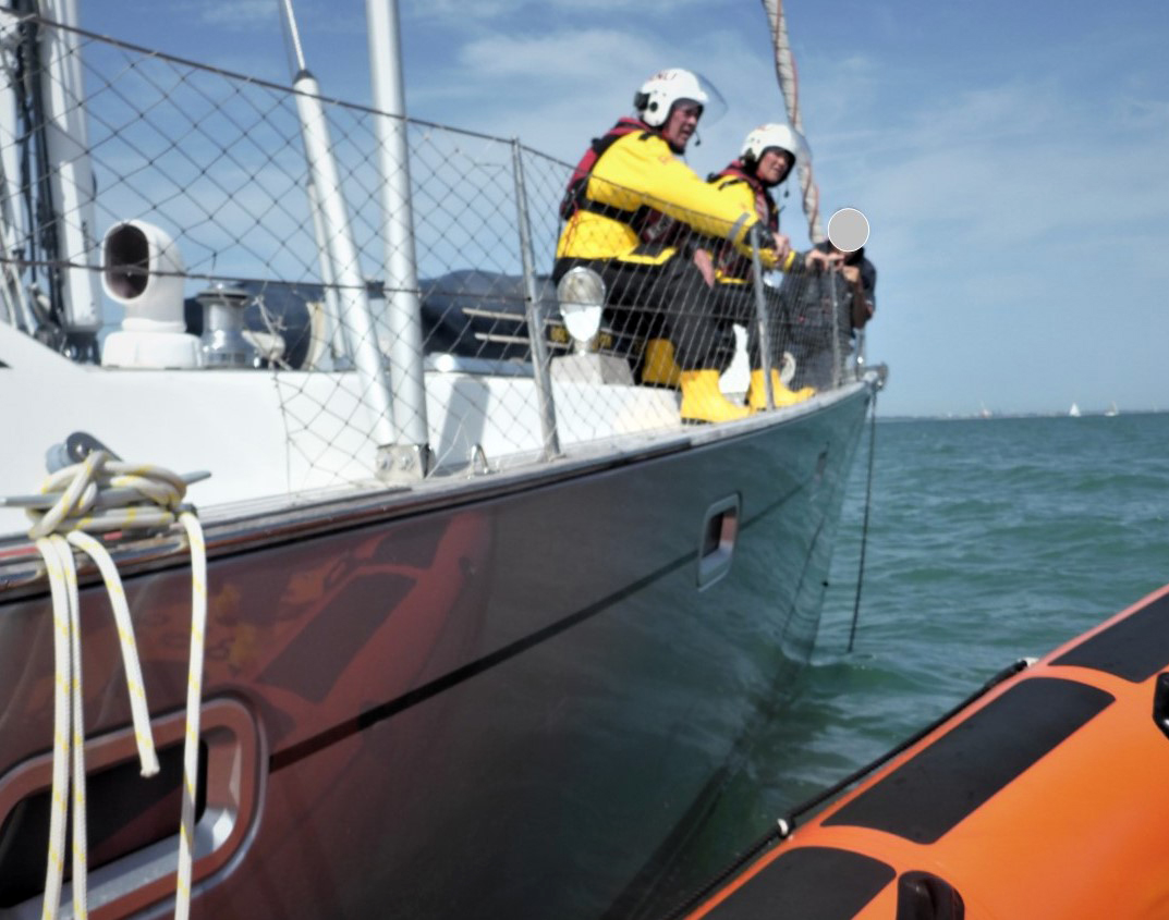 Two lifeboat members are on the yacht, looking down on the anchor chain.
