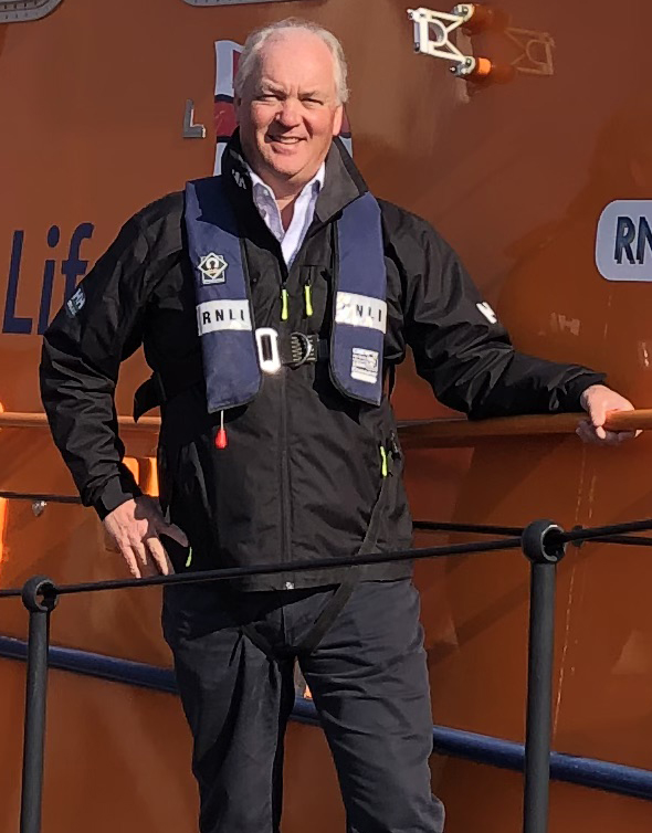 Mark Dowie stood on the side of Salcombe RNLI's Tamar class lifeboat 