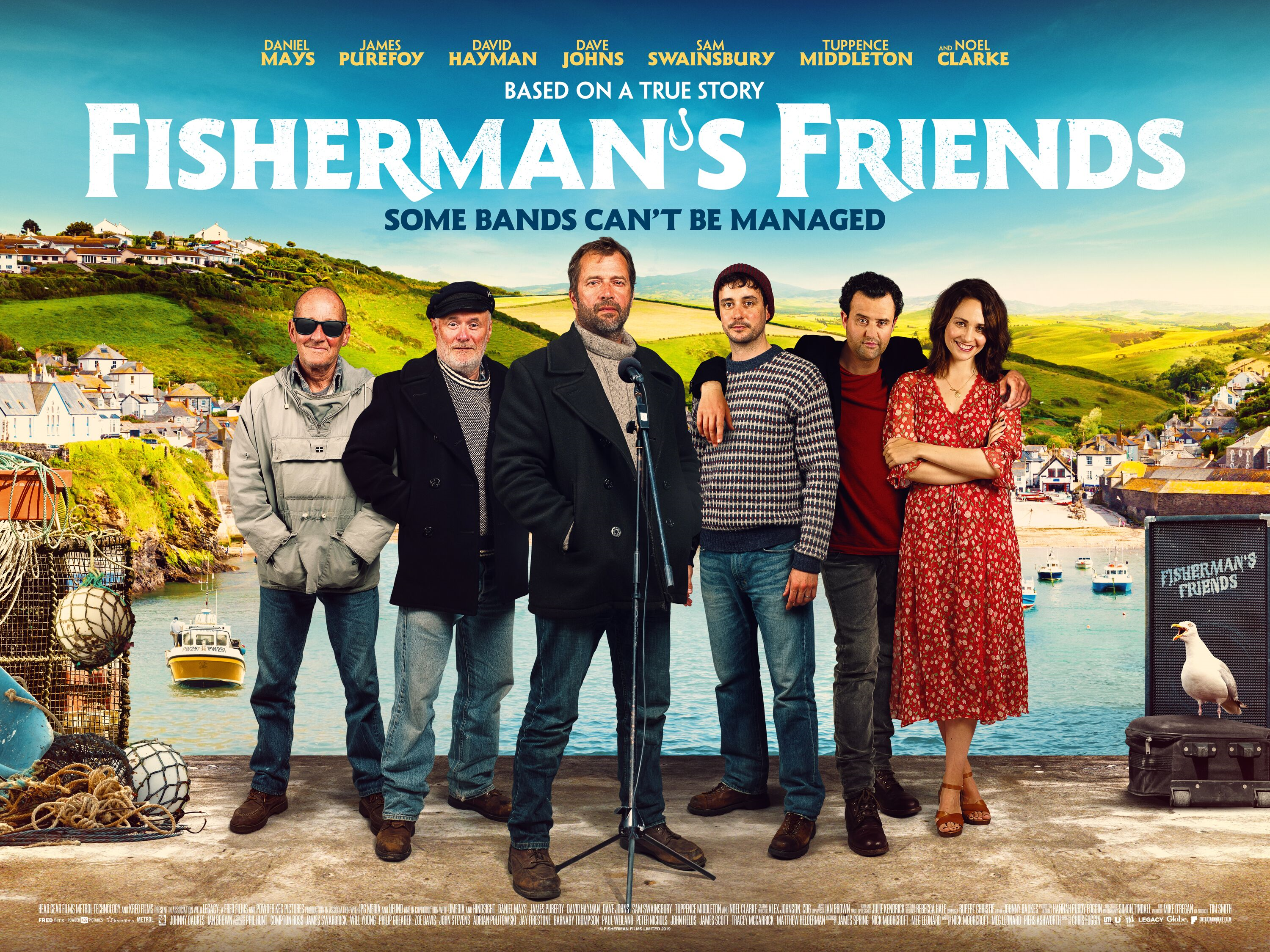 Cast members of the Fisherman's Friends film stood together with the coast in the background