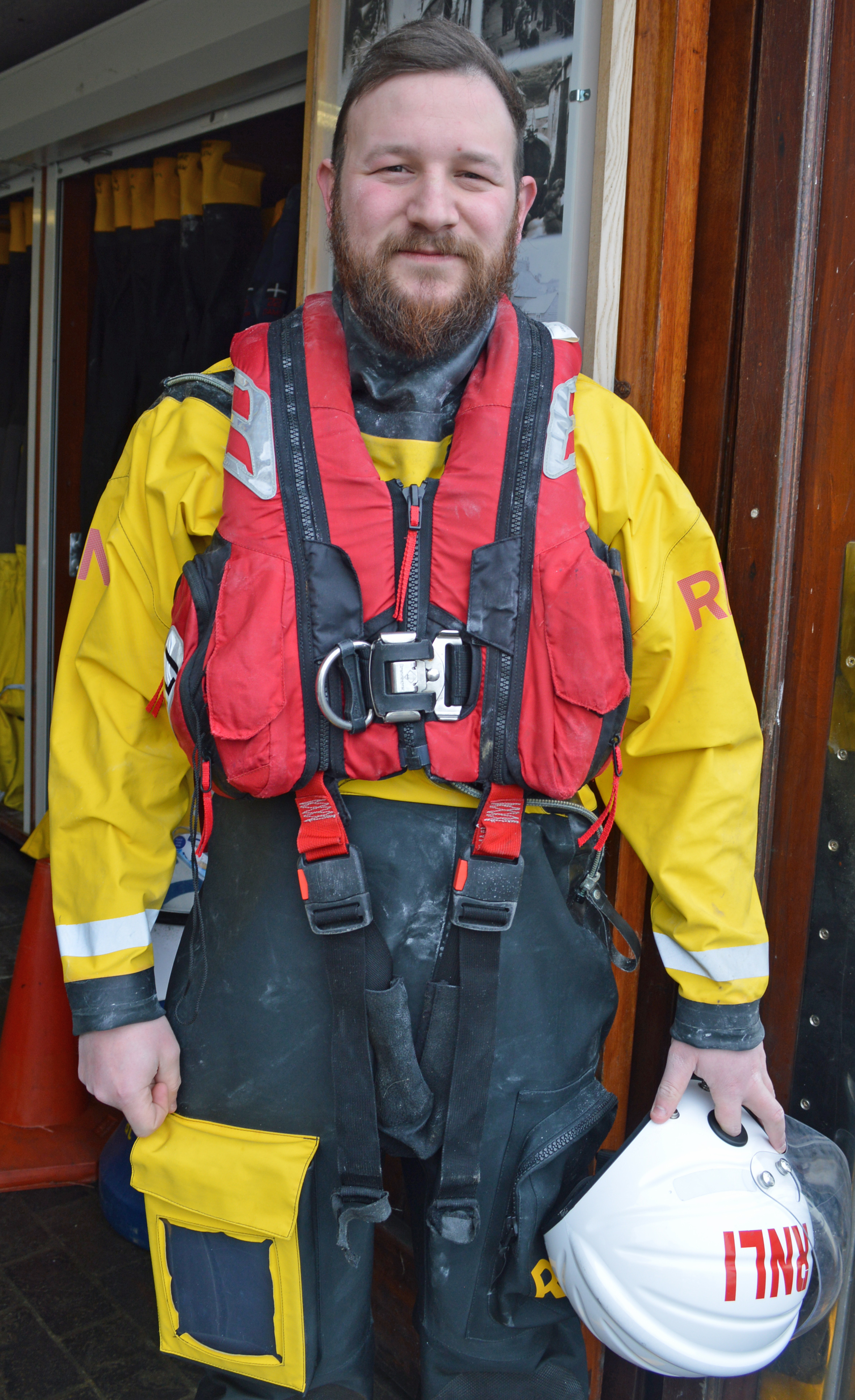 George in his crew kit holding his helmet at the station