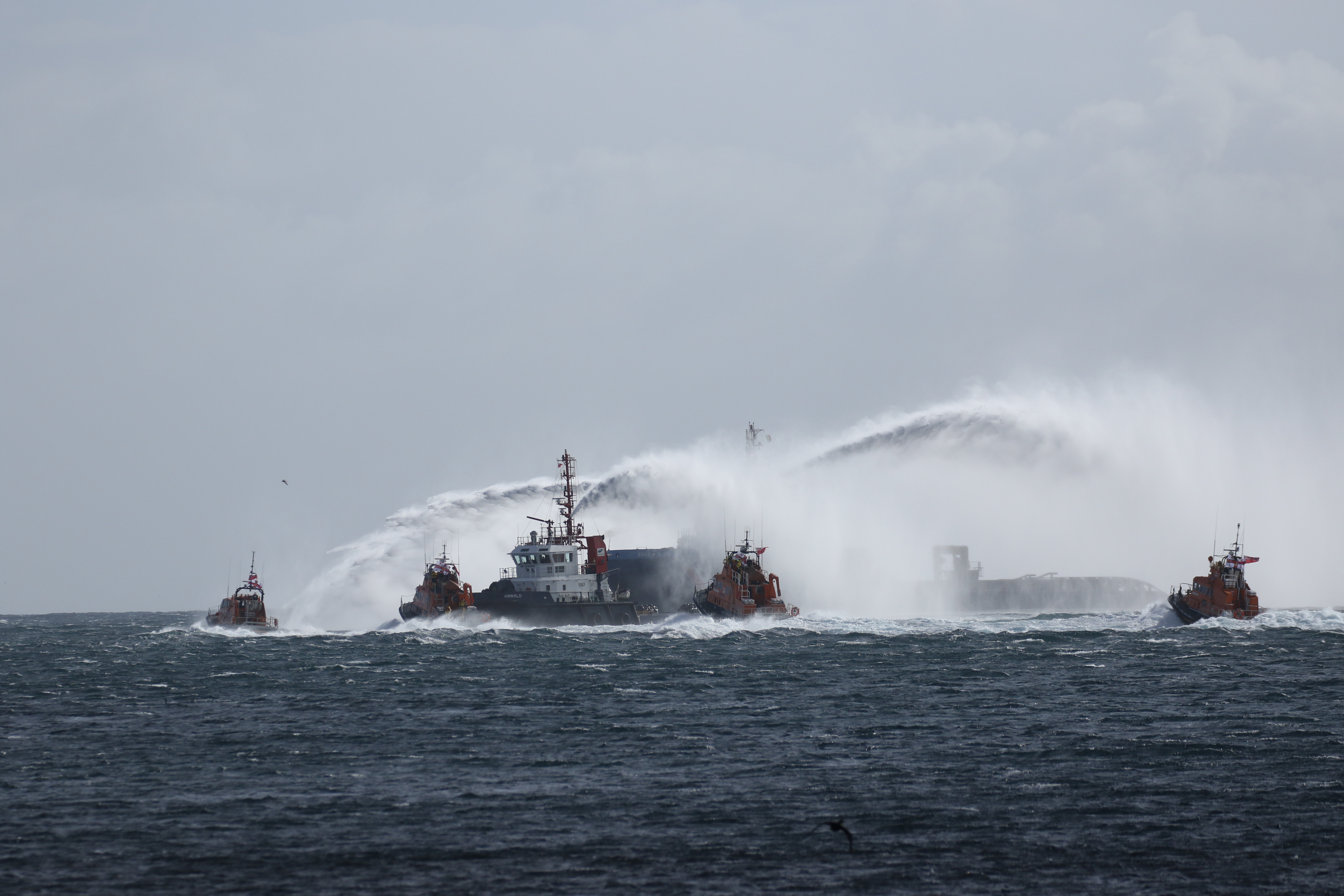 Coastguard and Orkney Harbour tugs form an arch with their fire hoses as RNLI lifeboats from Longhope, Stromness, Wick and Thurso pass by