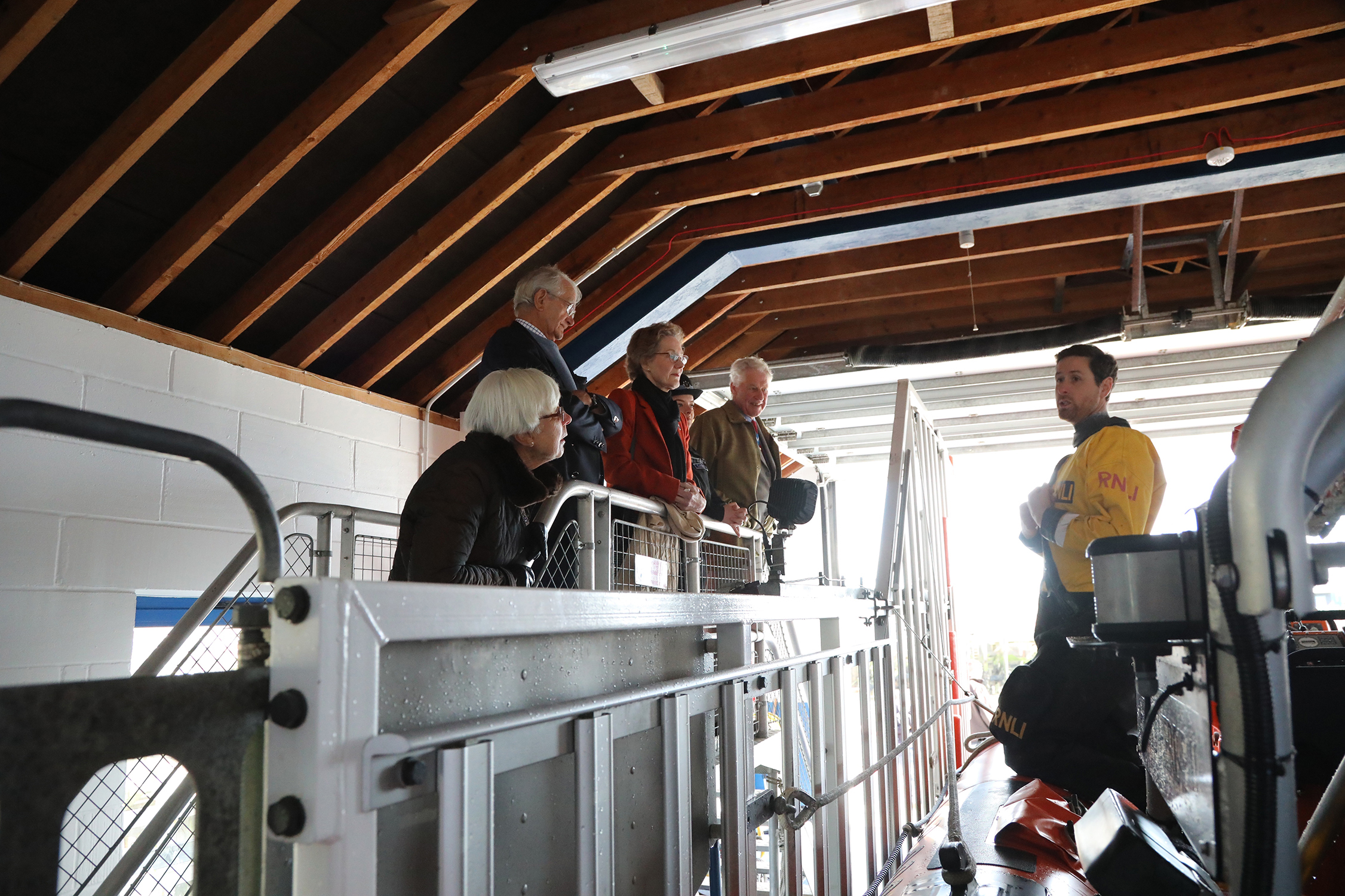 Designate Helm Matt Ellis stands on the Atlantic 85 inshore lifeboat explaining its working to the High Sheriff and party