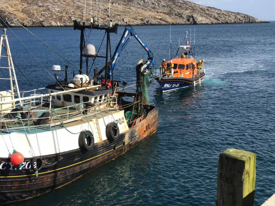 Leverburgh RNLI Lifeboat to the stern of the casualty vessel with line attached.