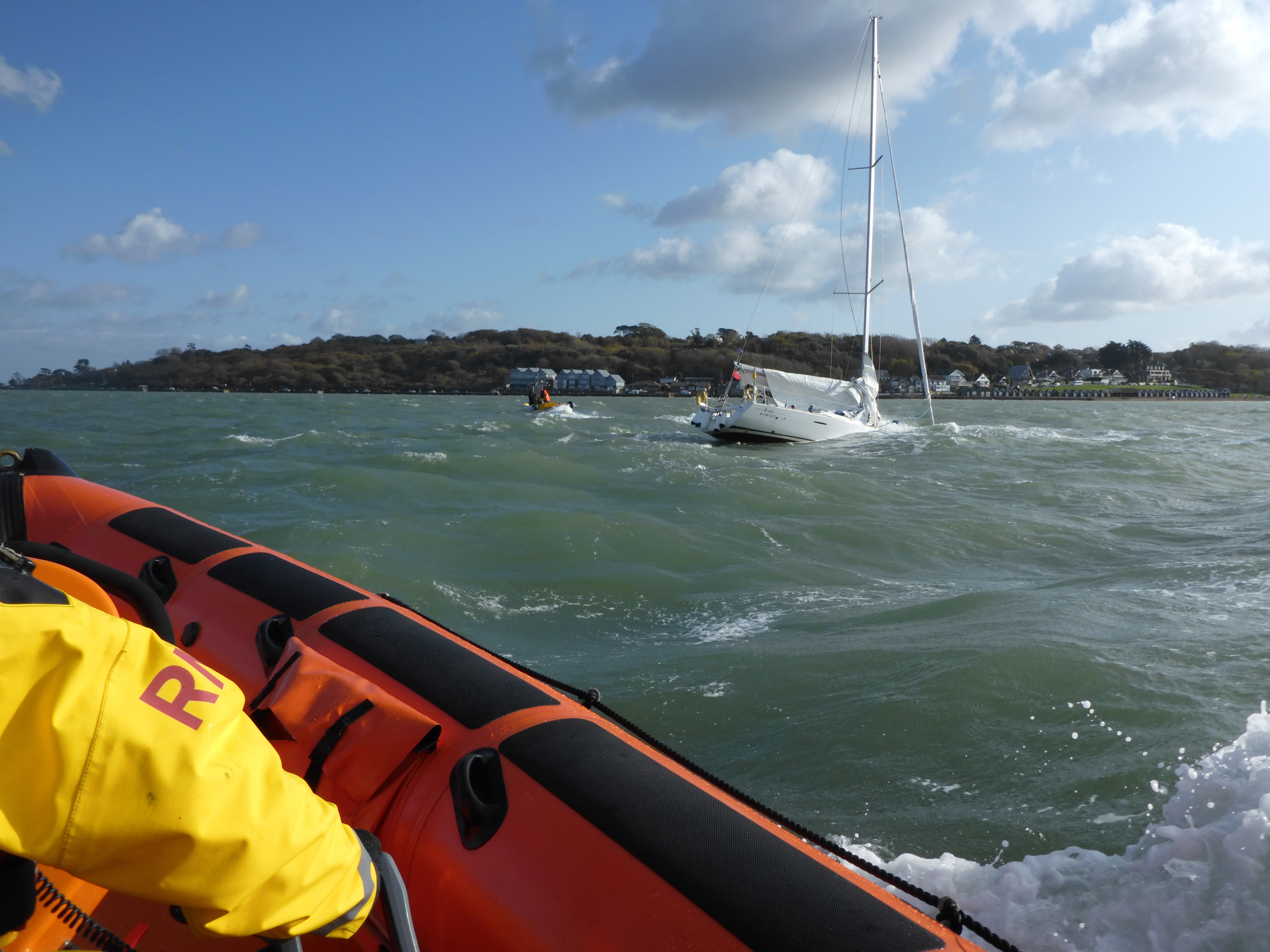 Wider shot of the crew and sinking yacht disappearing into the water.