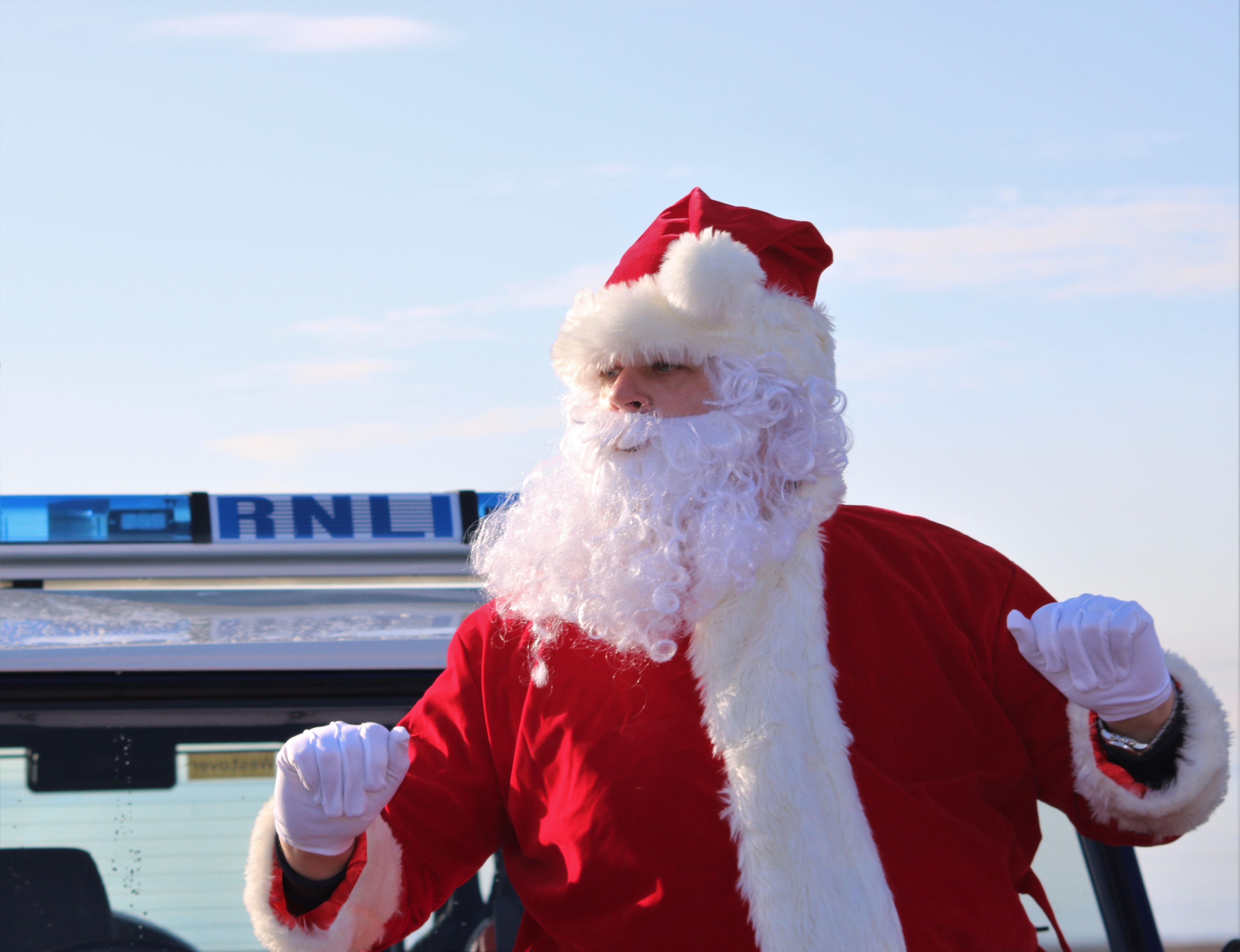 Santa singing a chorus of Jingle Bells with those waiting on the beach
