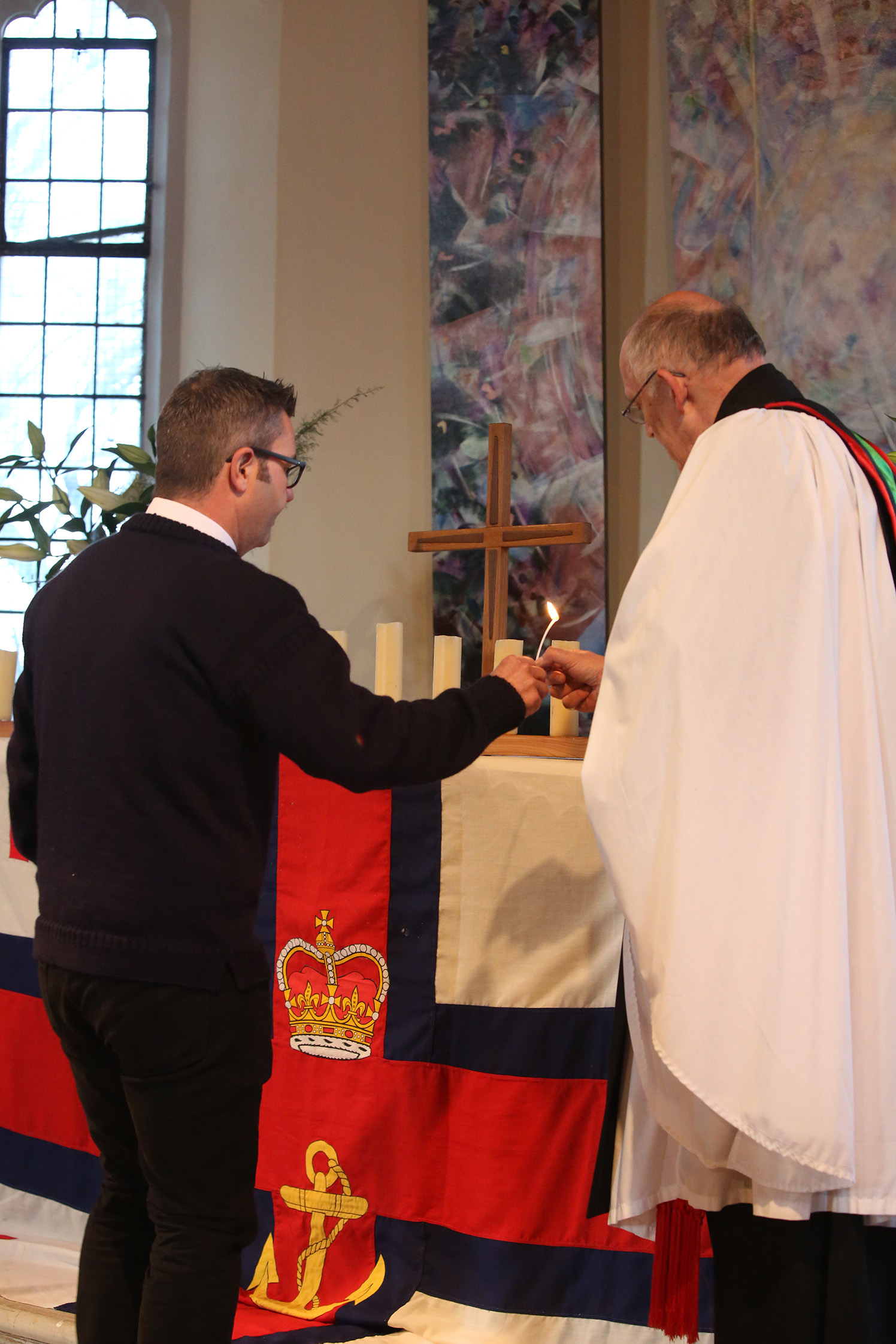 Stuart Clark is handed a taper by Canon David Frost so that the candle may be lit