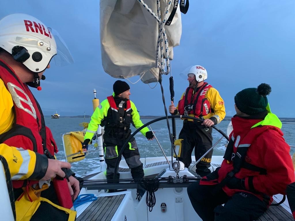 Photo showing the RNLI volunteers on board the yacht with its crew.