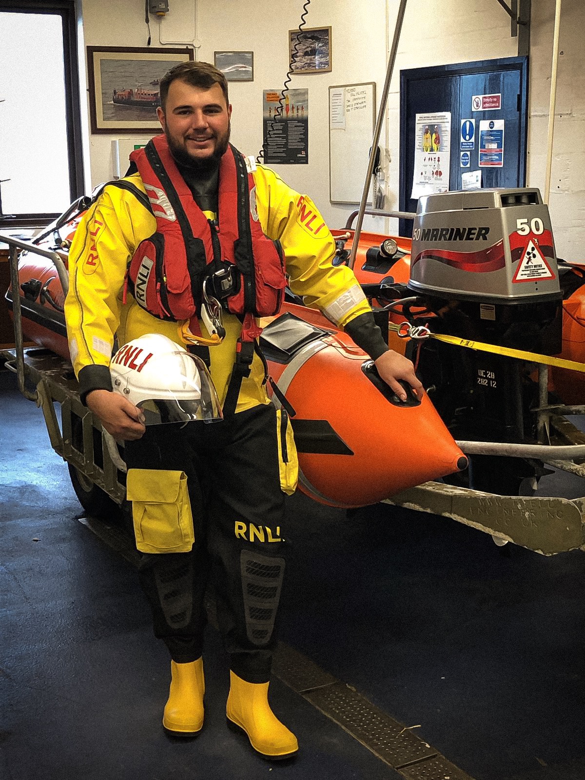 Josh Double in full drysuit next to the Mumbles inshore lifeboat Mark Lott