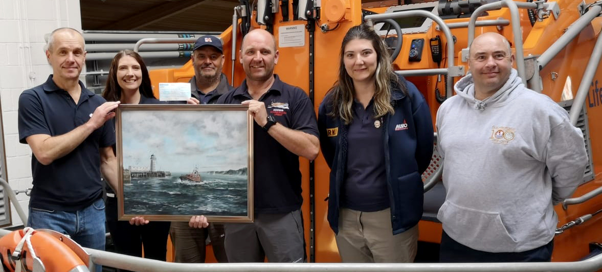 The photos shows, L-R, Jim giving the picture back to lifeboat shop volunteer (and Severfield employee) Susanna Dunn, crew member John Huntley, coxswain Lee Marton and crew members Tabz Nixon and Mark Jenkinson