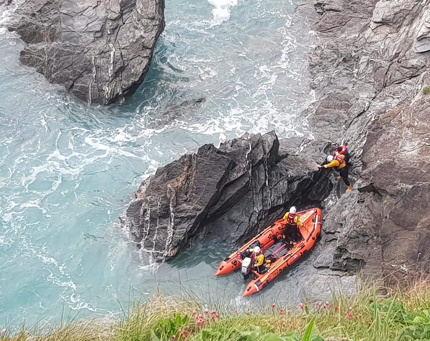 View from the clifftop as Newquay RNLI crew rescue woman from rocks in D class inshore lifeboat