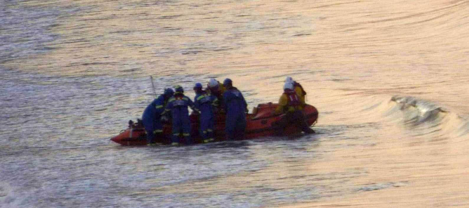 Lifeboat crew and coastguards lift the casualty from the lifeboat in the north bay