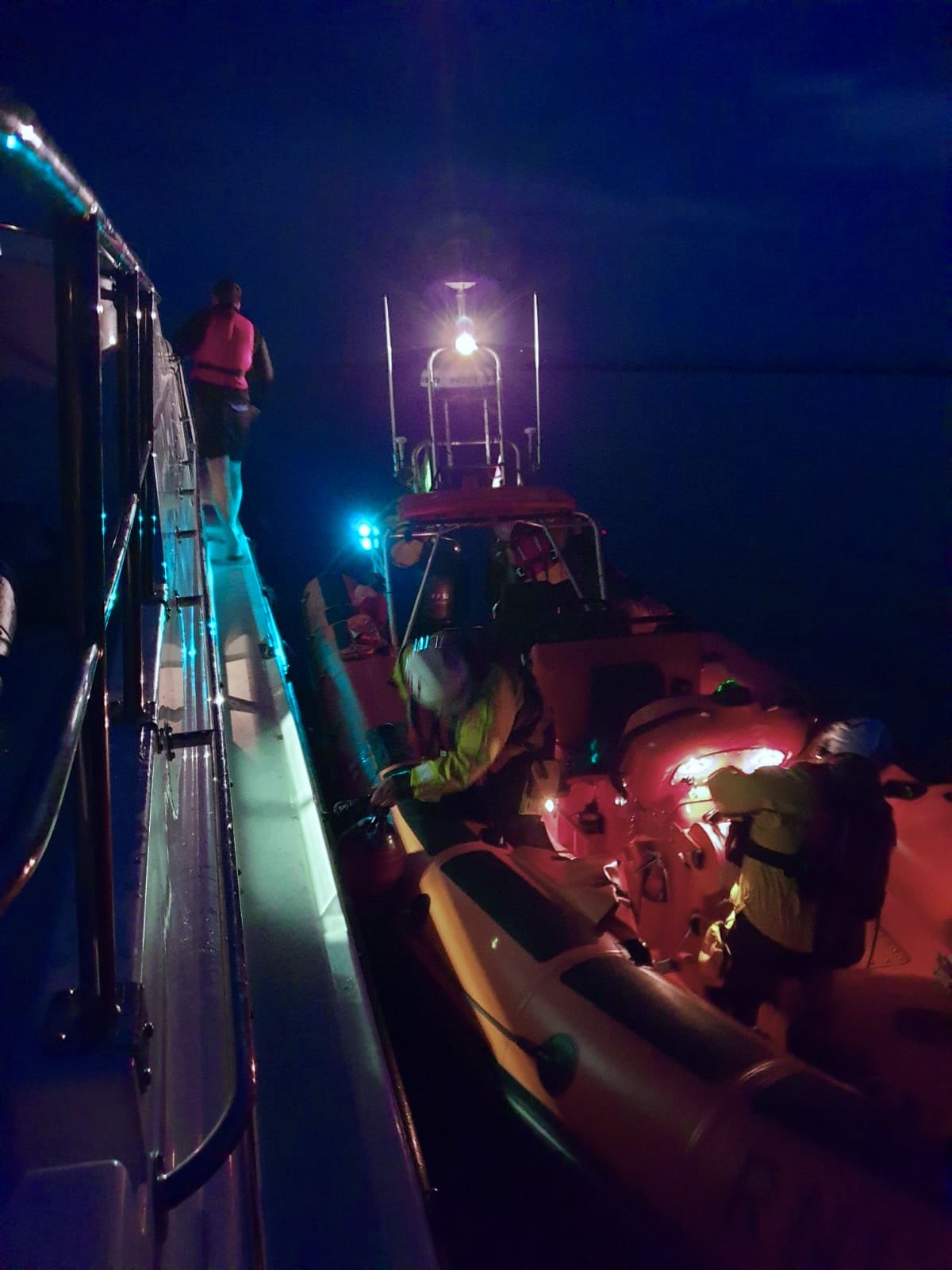 Lifeboat alongisde casualty vessel, a dark night lit only by the lifeboats naviagtion lights