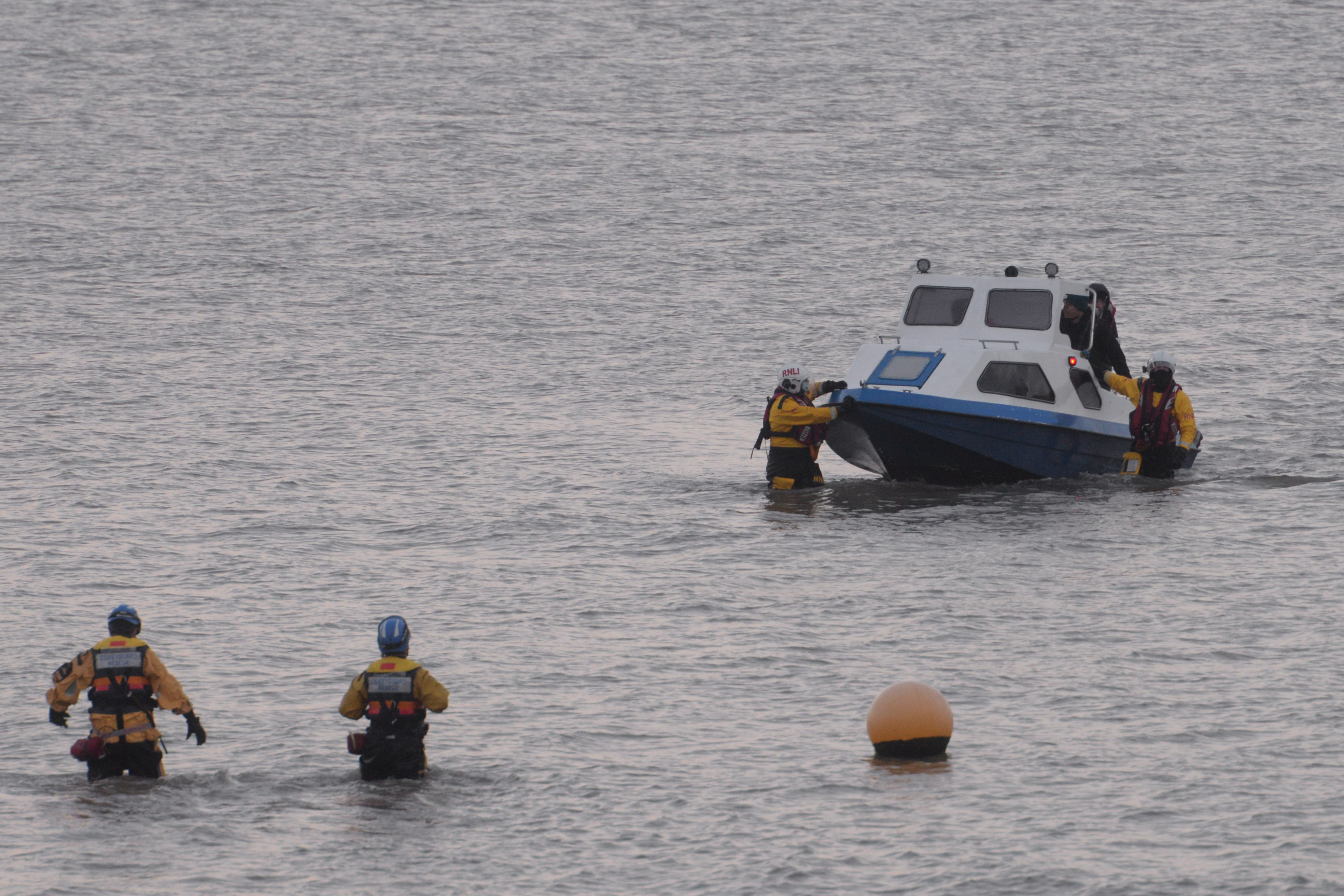 Two members of the Whitstable lifeboat crew 'walk' the broken down angling dory and it's three occupants ashore to be met by members of the Herne Bay Coastguard Rescue Team at Herne Bay on Saturday morning